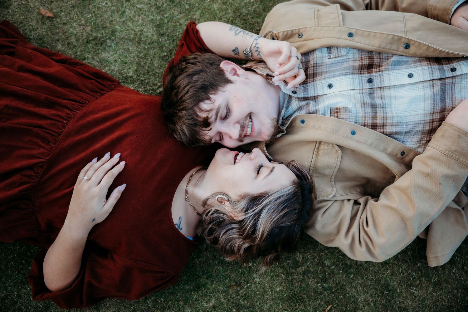 Couple in casual clothing sharing intimate moment while lying on grass.