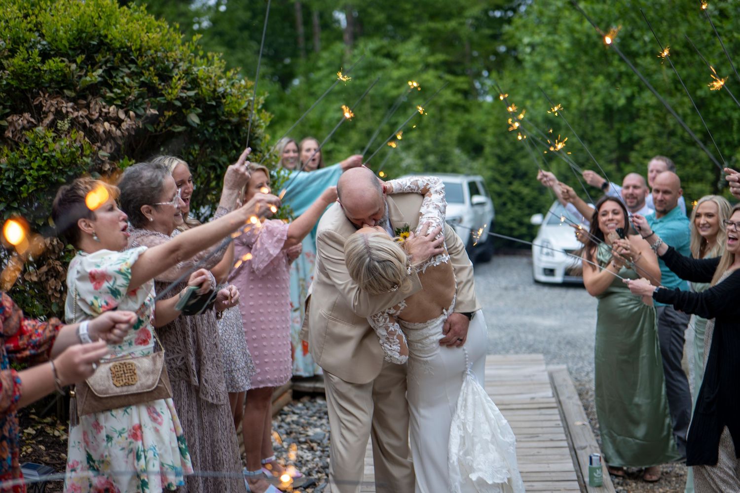 Wedding party and guests celebrate with sparklers creating a magical outdoor evening atmosphere.