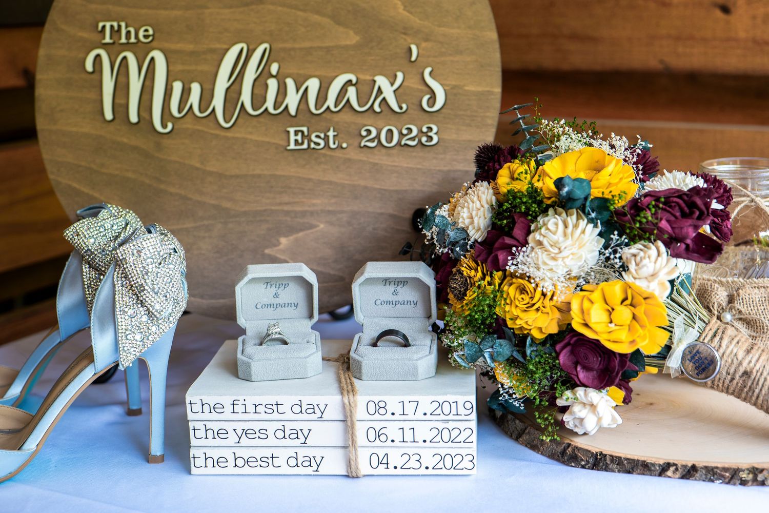 Wedding details display with personalized wooden sign, blue shoes, and vibrant bouquet.