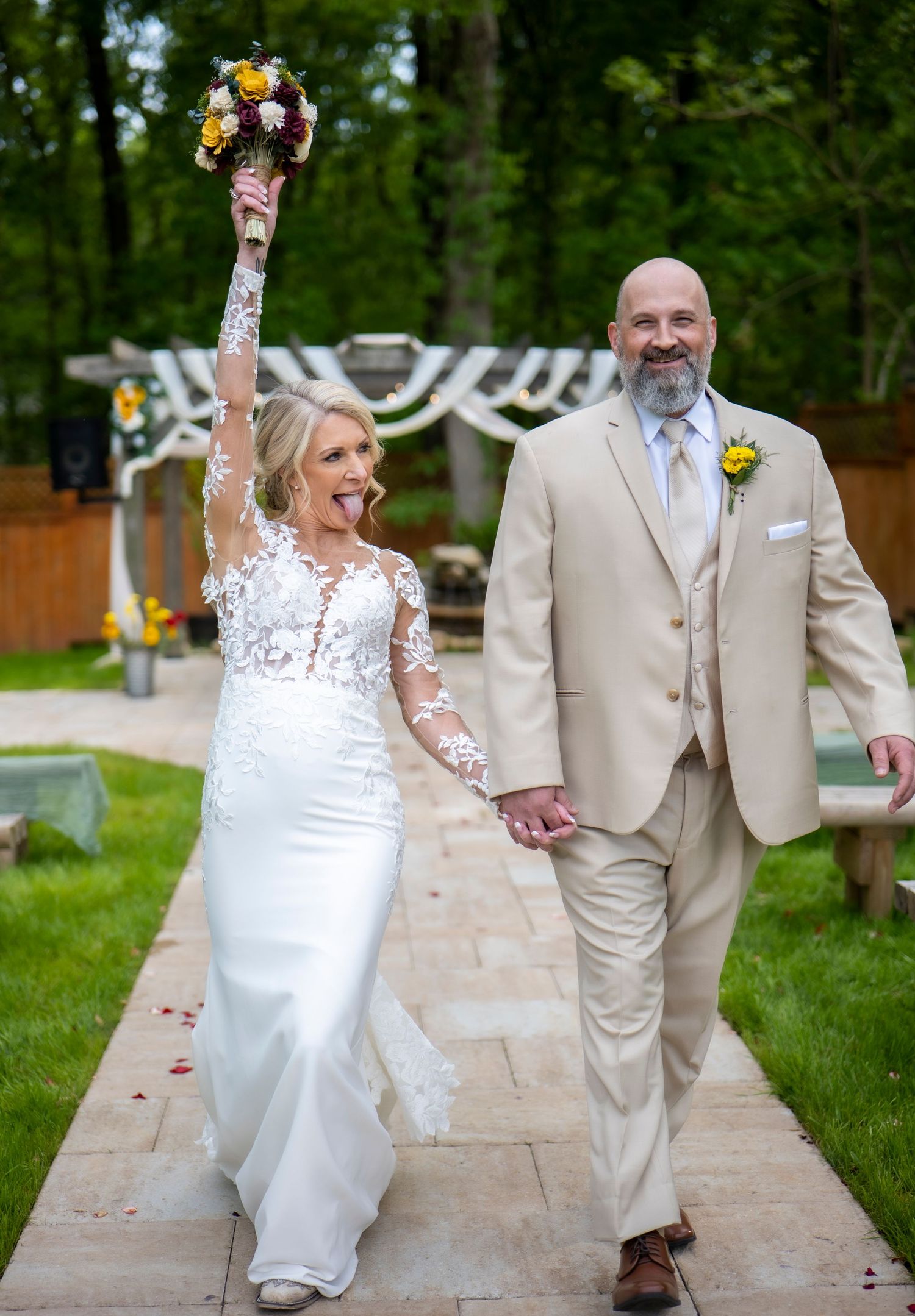 Couple celebrating their wedding day walking on stone pathway with floral bouquet.