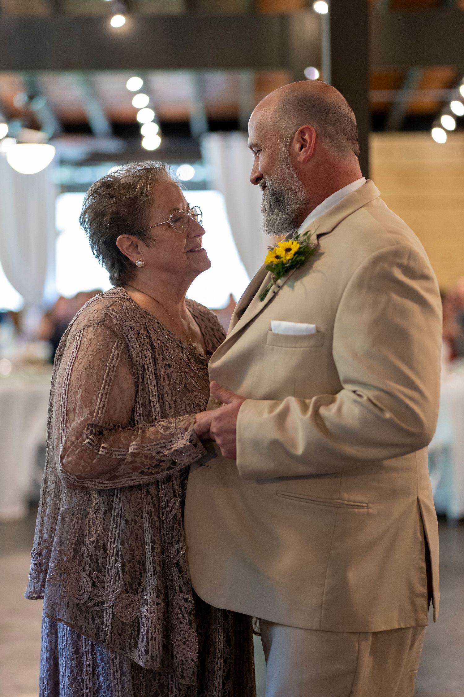 Tender dance moments captured during wedding reception in warm indoor lighting.