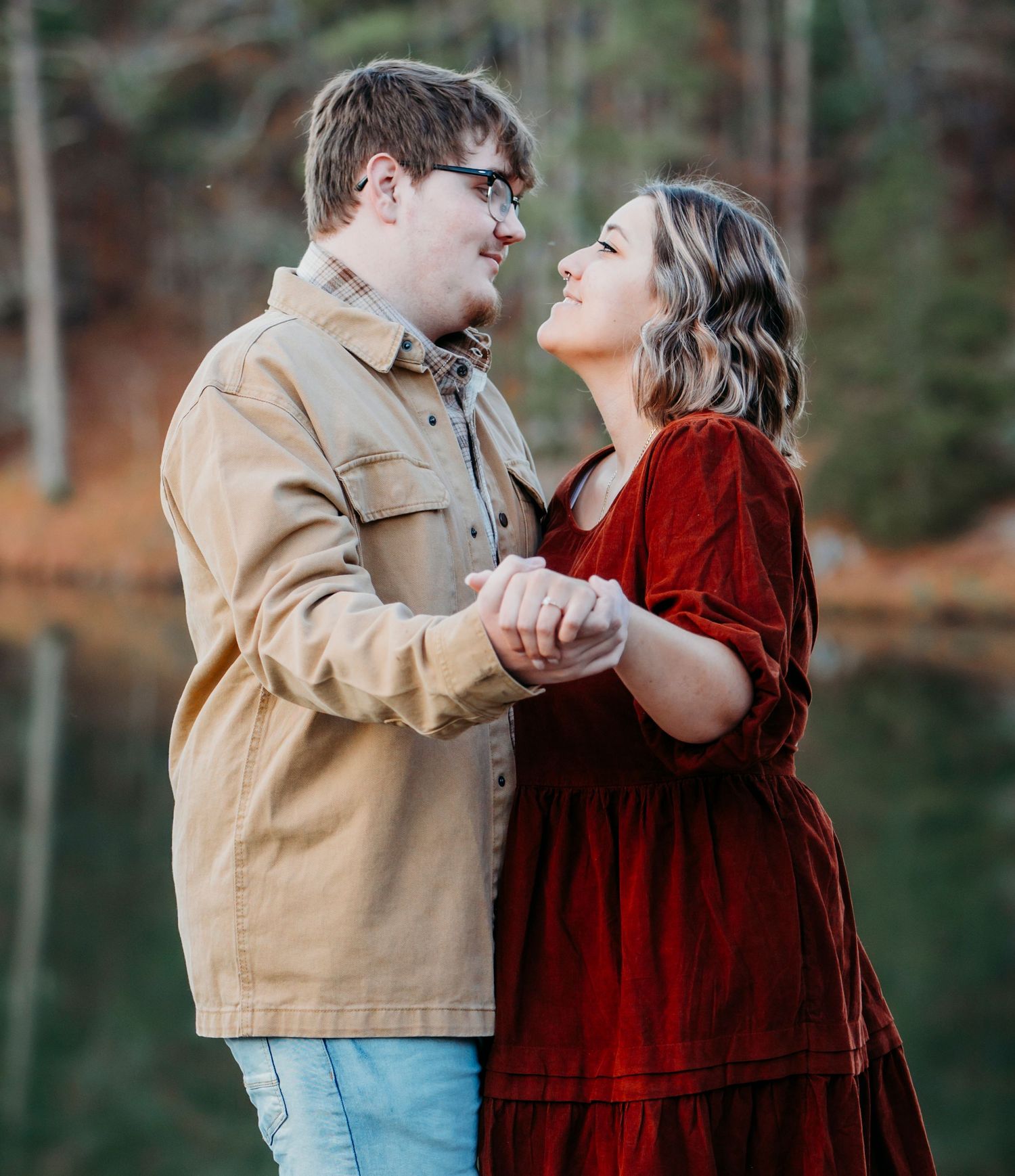 A couple dances together near a scenic lake surrounded by autumn trees.
