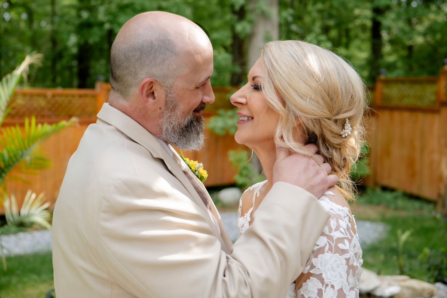 Romantic garden wedding portraits with stone patio and wooden fence backdrop.