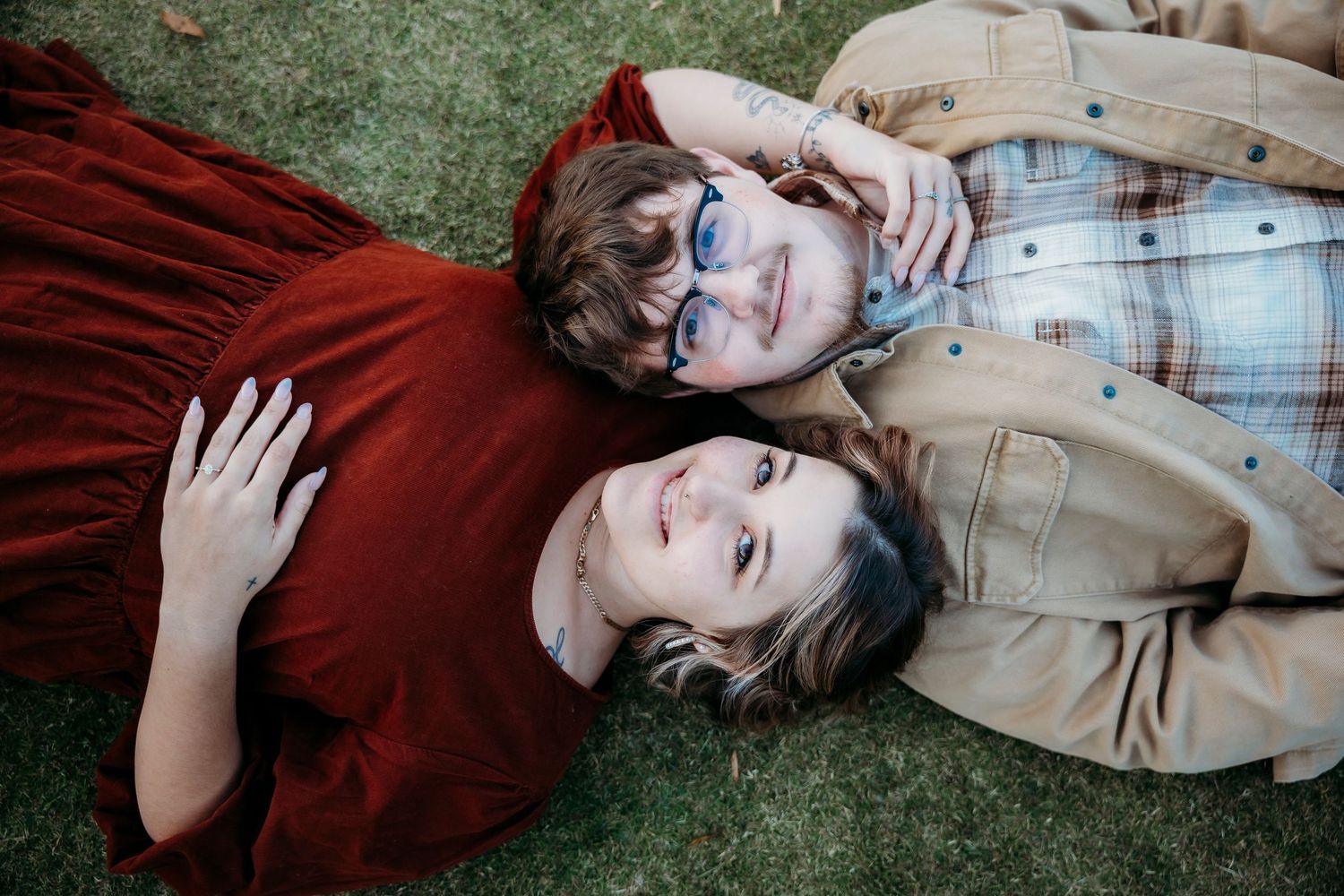Romantic engagement photo of couple relaxing on green lawn.