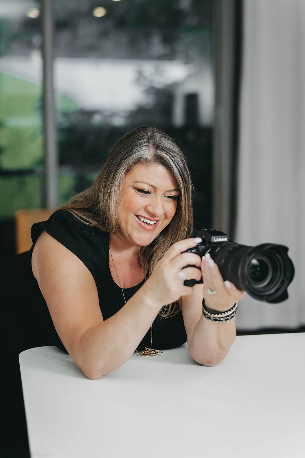 Photographer reviewing images on camera while working at desk.