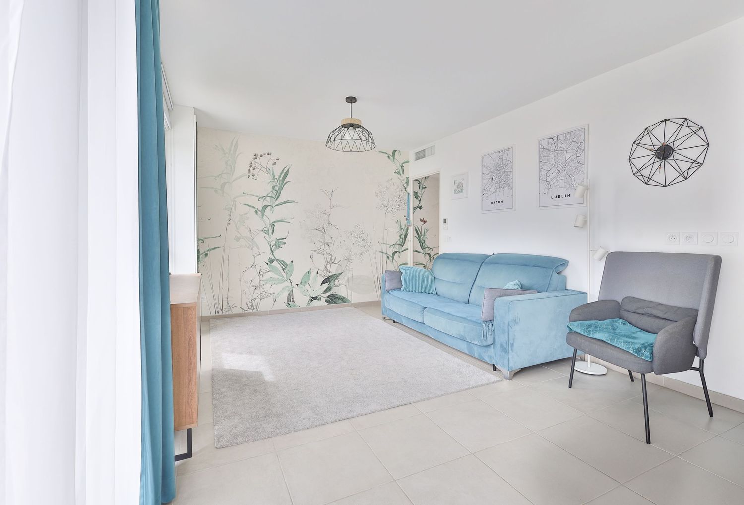 Modern living room with blue sofa, floral wallpaper accent wall, and minimalist Scandinavian decor.