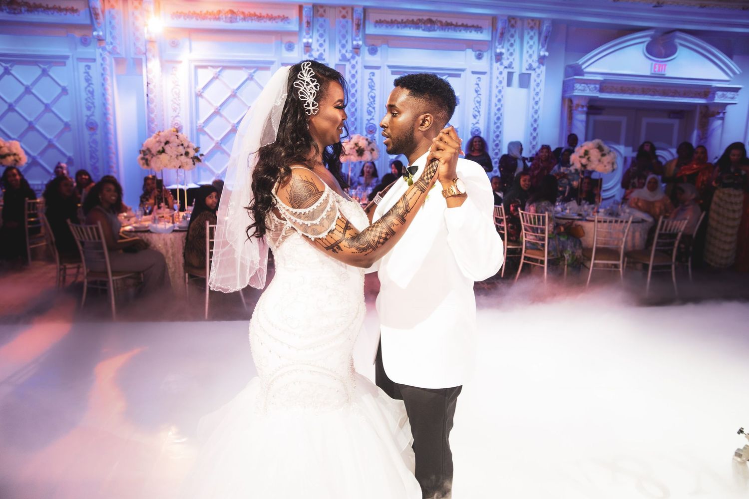 Bride and groom share their first dance on misty white dance floor at elegant wedding reception.