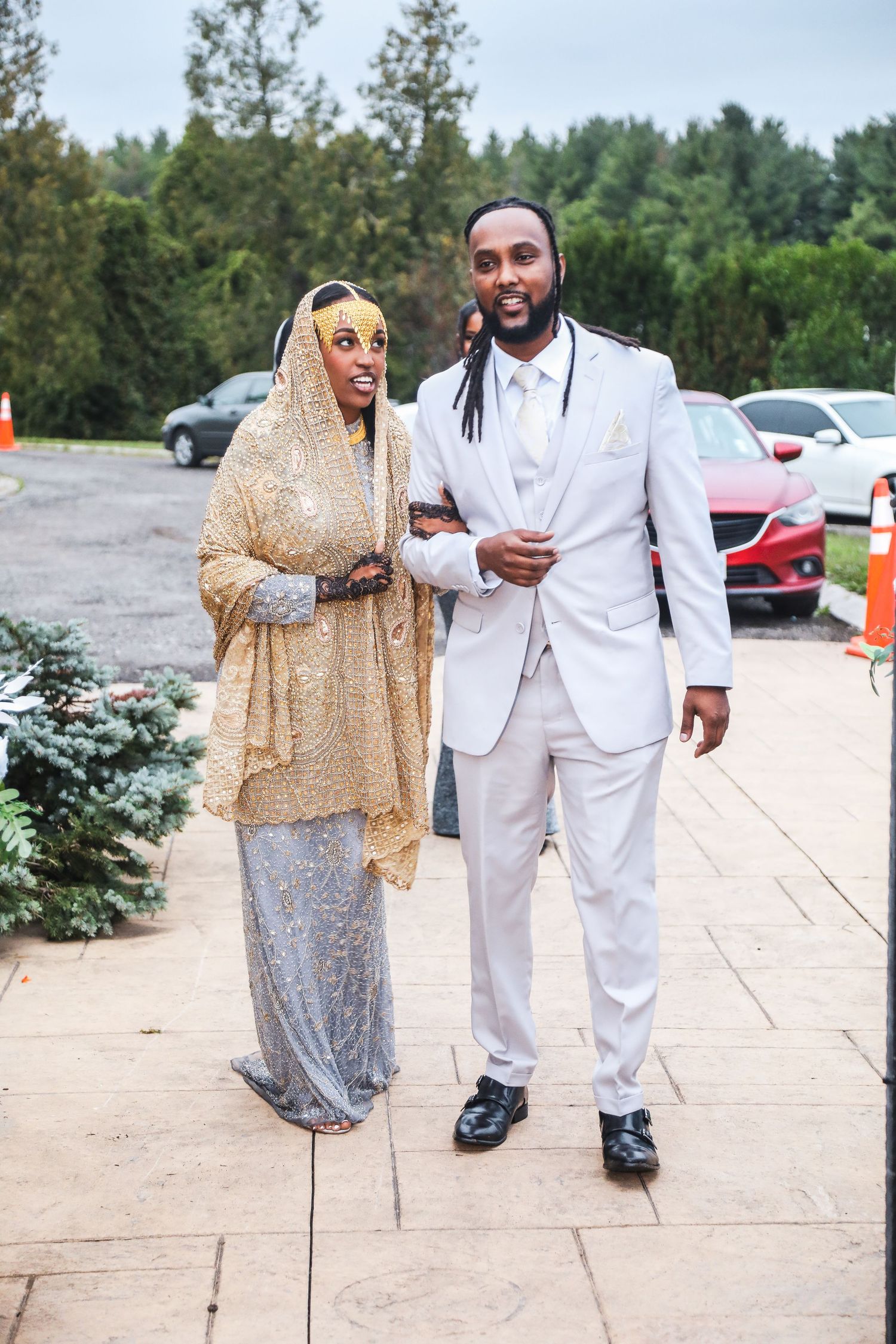 Couple in formal attire walking together on stone pathway.