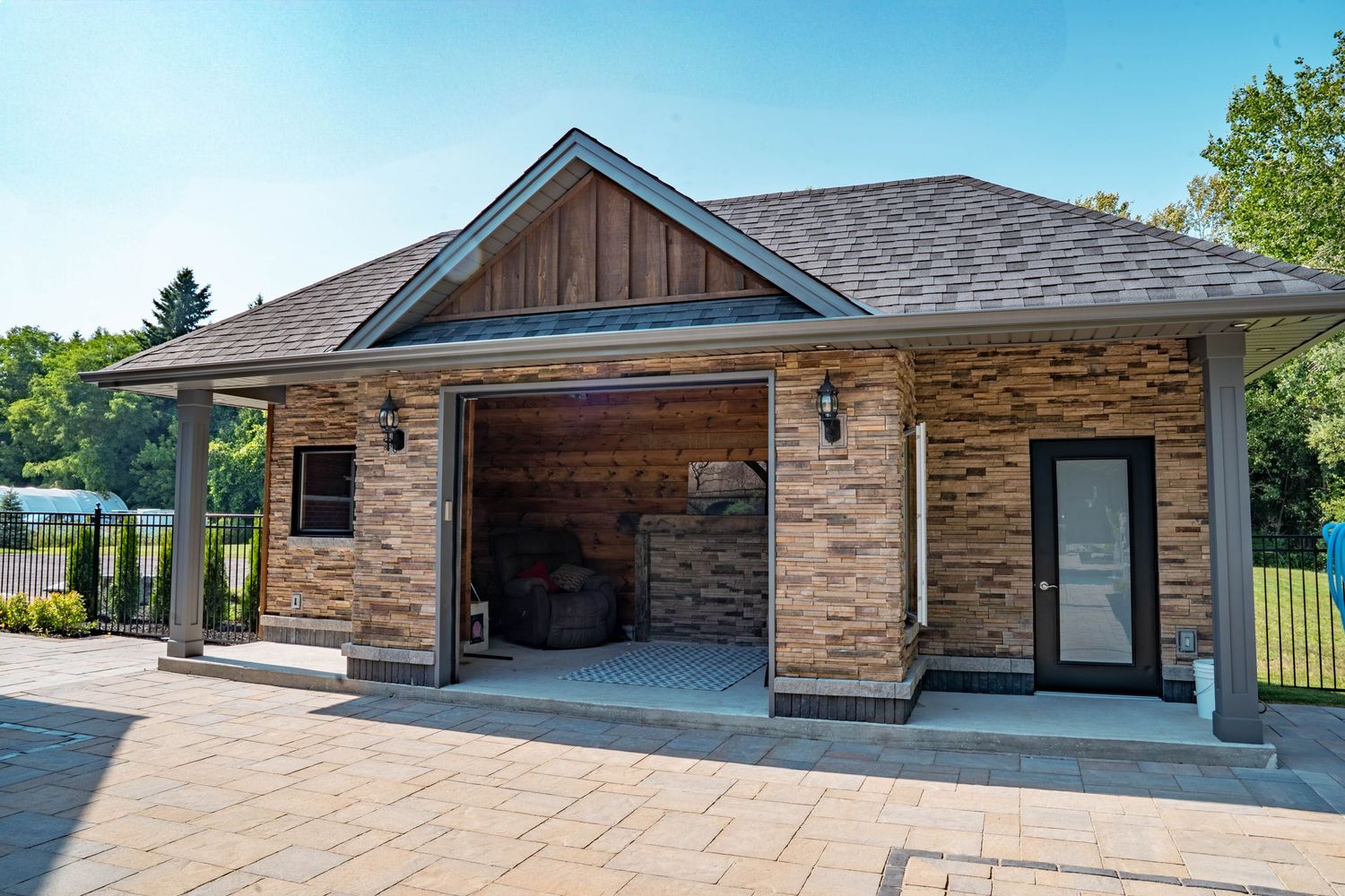 Modern ranch-style home exterior showcasing a stone facade, attached garage, and landscaped front yard.