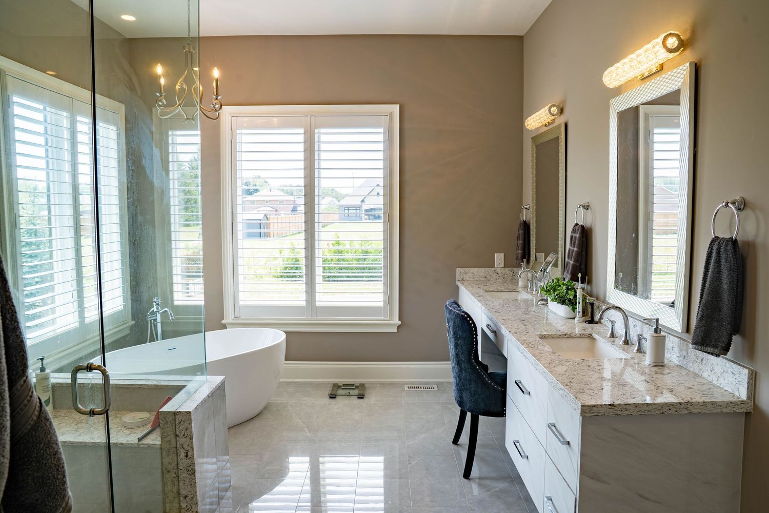 Modern bathroom interior with white cabinets, marble countertops, and natural lighting from multiple windows.