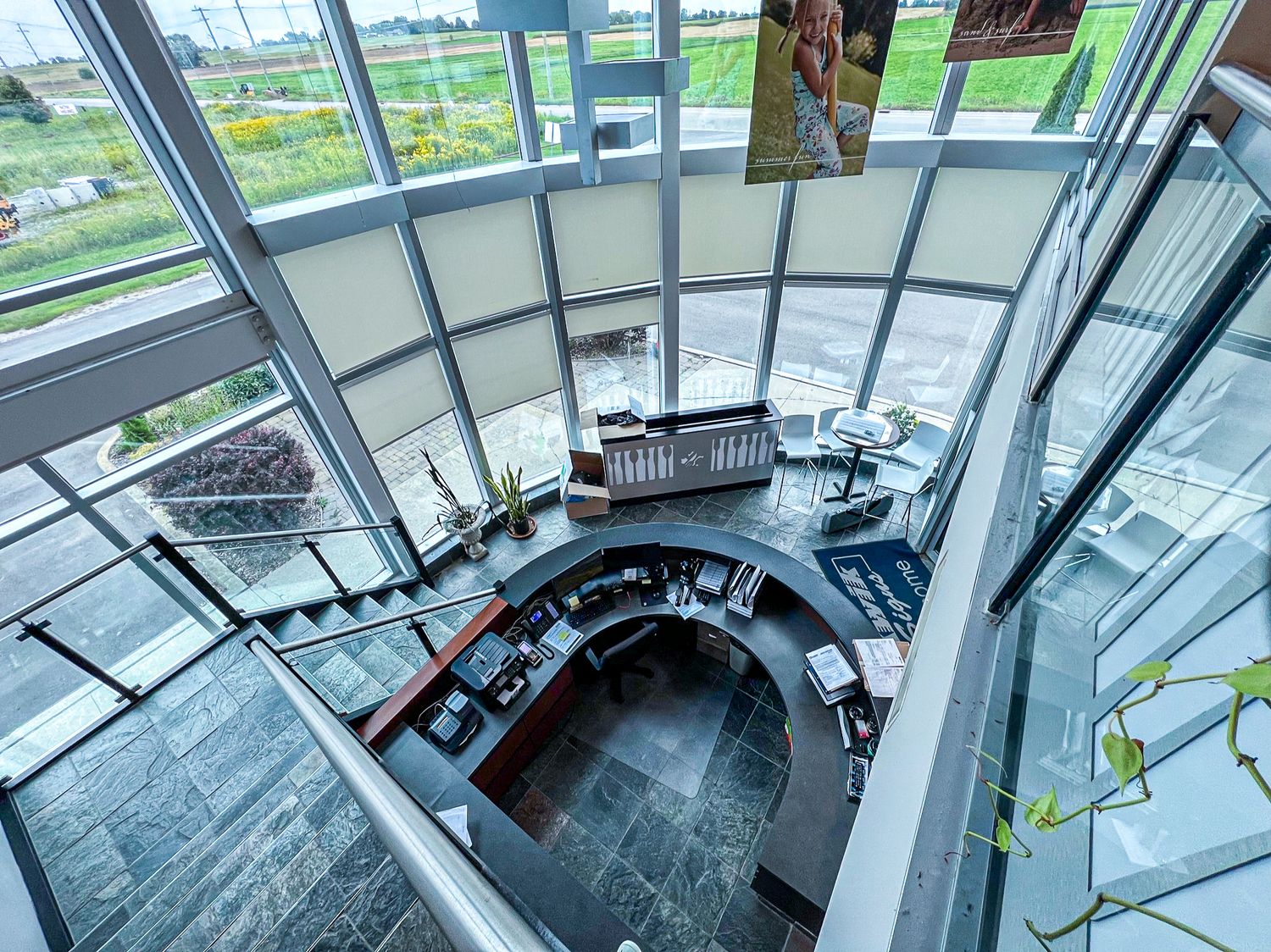 Curved modern staircase with floor-to-ceiling windows overlooking green landscape.