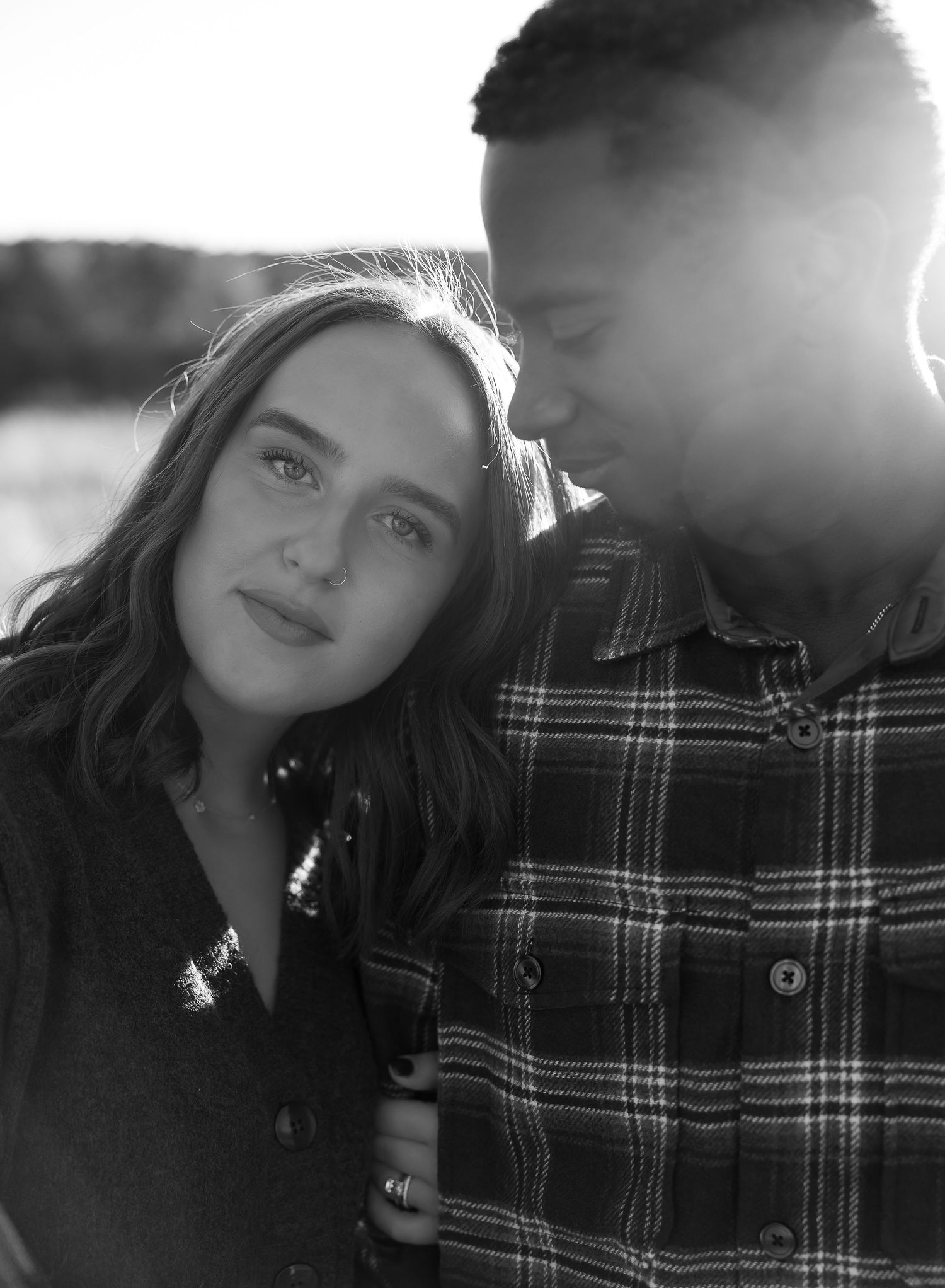 A romantic black and white portrait of a couple outdoors with sunlight creating a beautiful backlit effect.