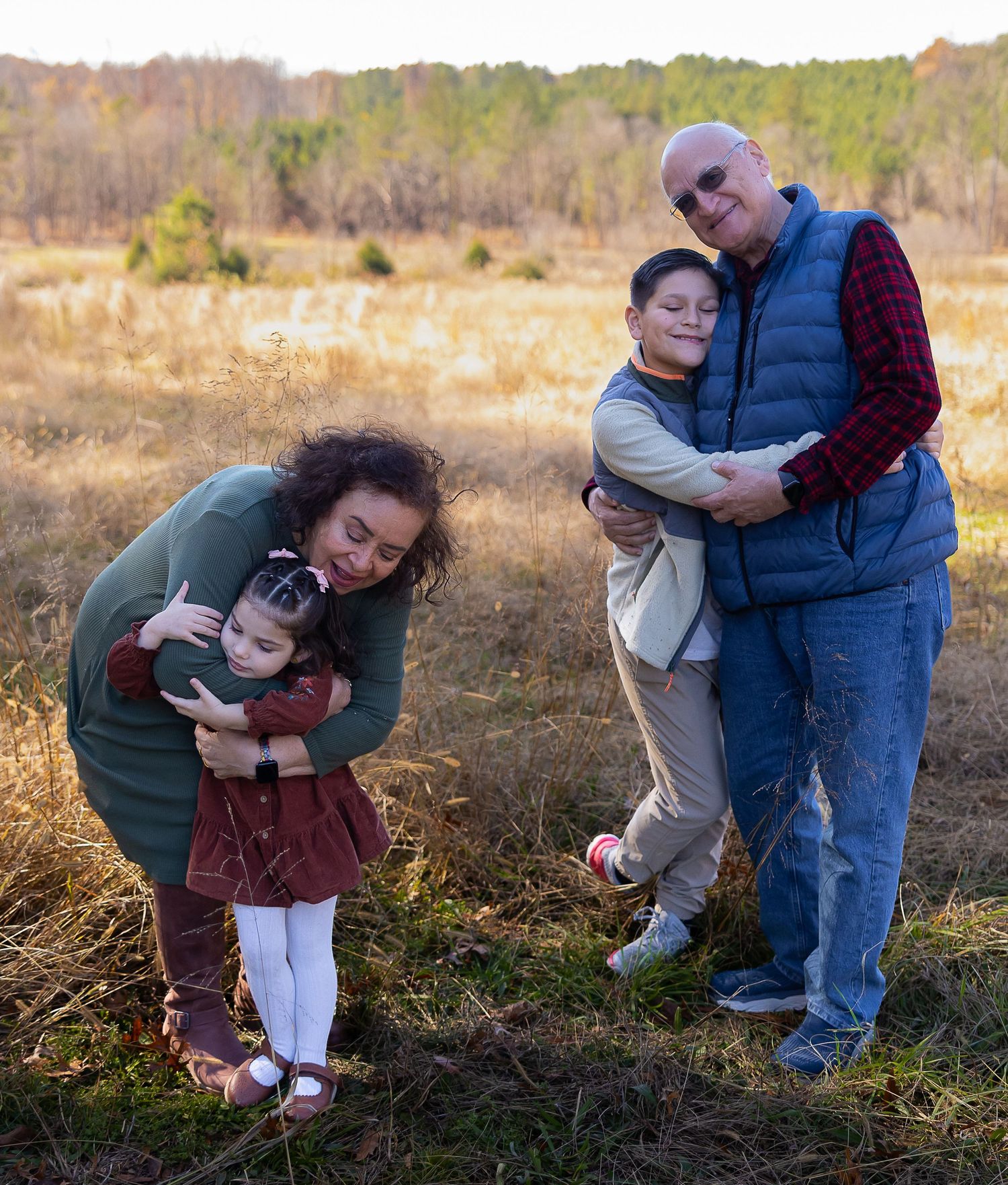 People playing and interacting with a small puppy in a grassy autumn field during golden hour.