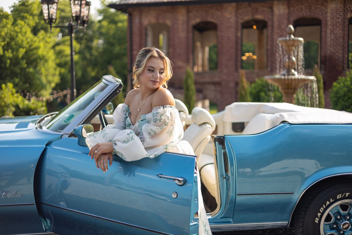A bride and groom ride in a vintage light blue convertible car during their wedding celebration.