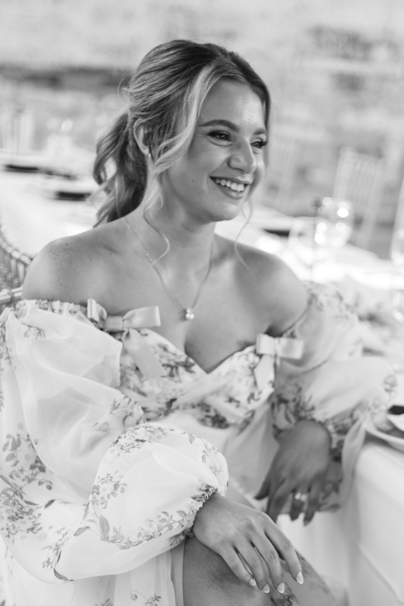 A group of bridesmaids in white dresses share joyful laughter during a wedding celebration.