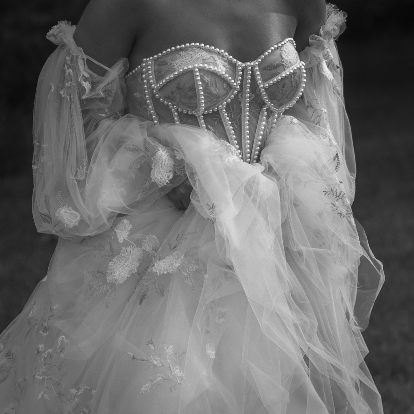 Detailed view of a white corset wedding dress bodice with beaded embellishments and sheer fabric.