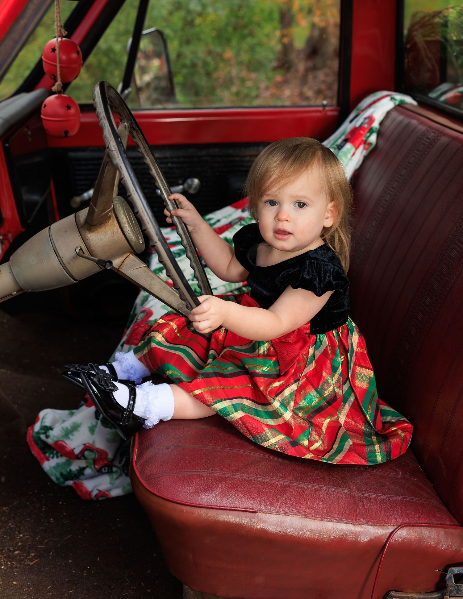 A sequence of photos showing a small child playing with a vintage car's steering wheel while wearing a festive dress.