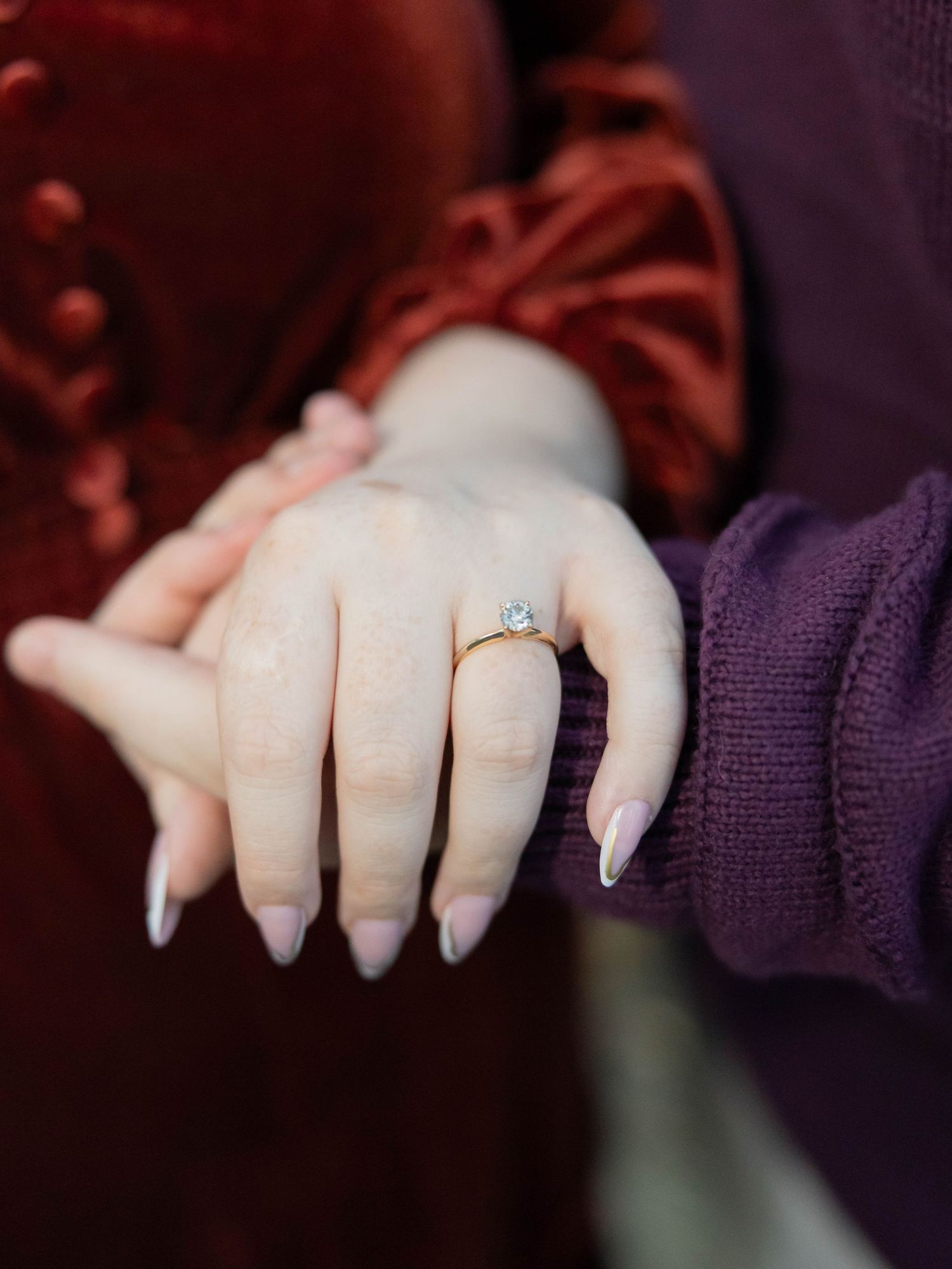 A sequence of close-up photos showing hands with long acrylic nails in a dark purple lighting environment.