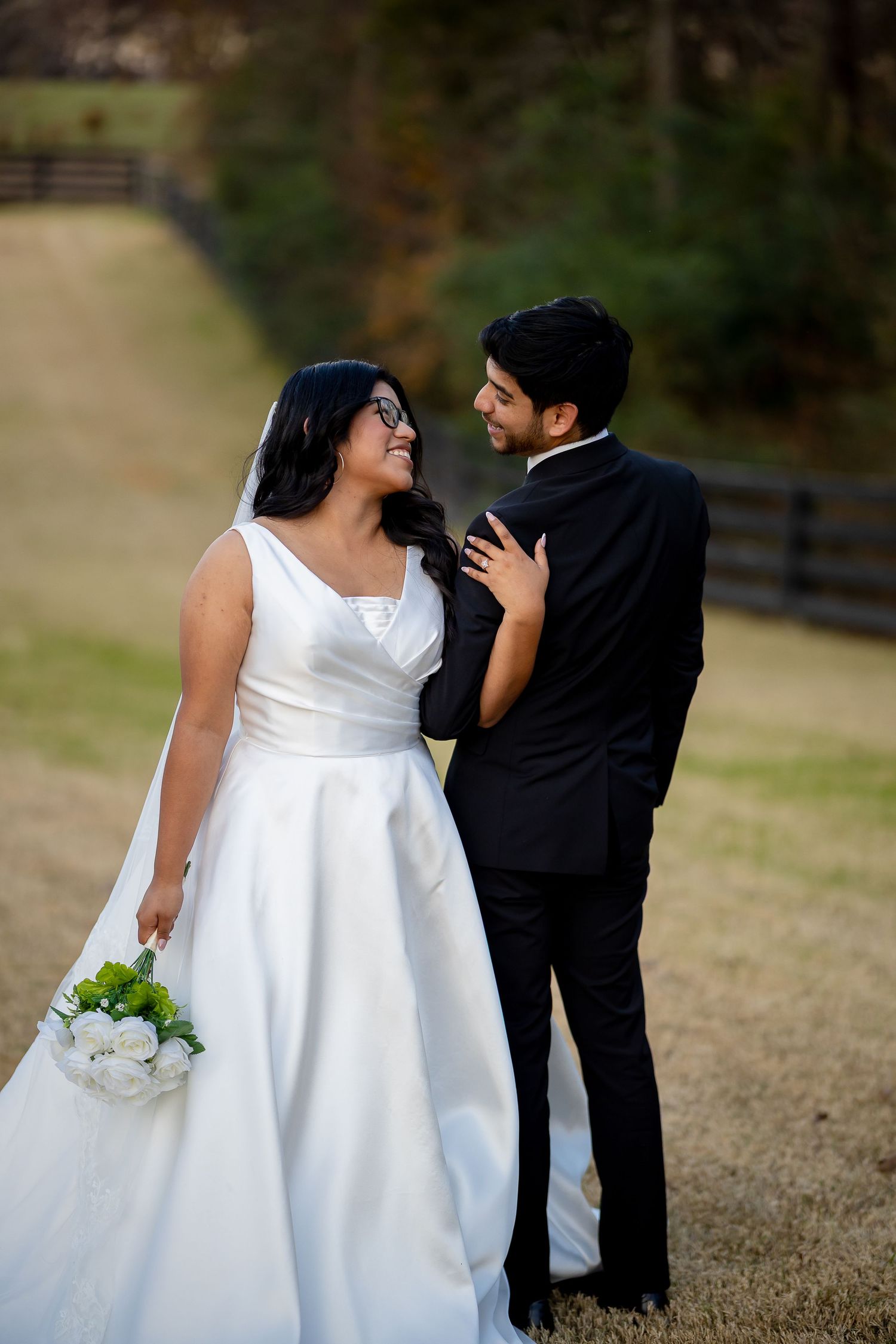Bride and groom sharing a joyful glance while posing together outdoors after wedding ceremony.