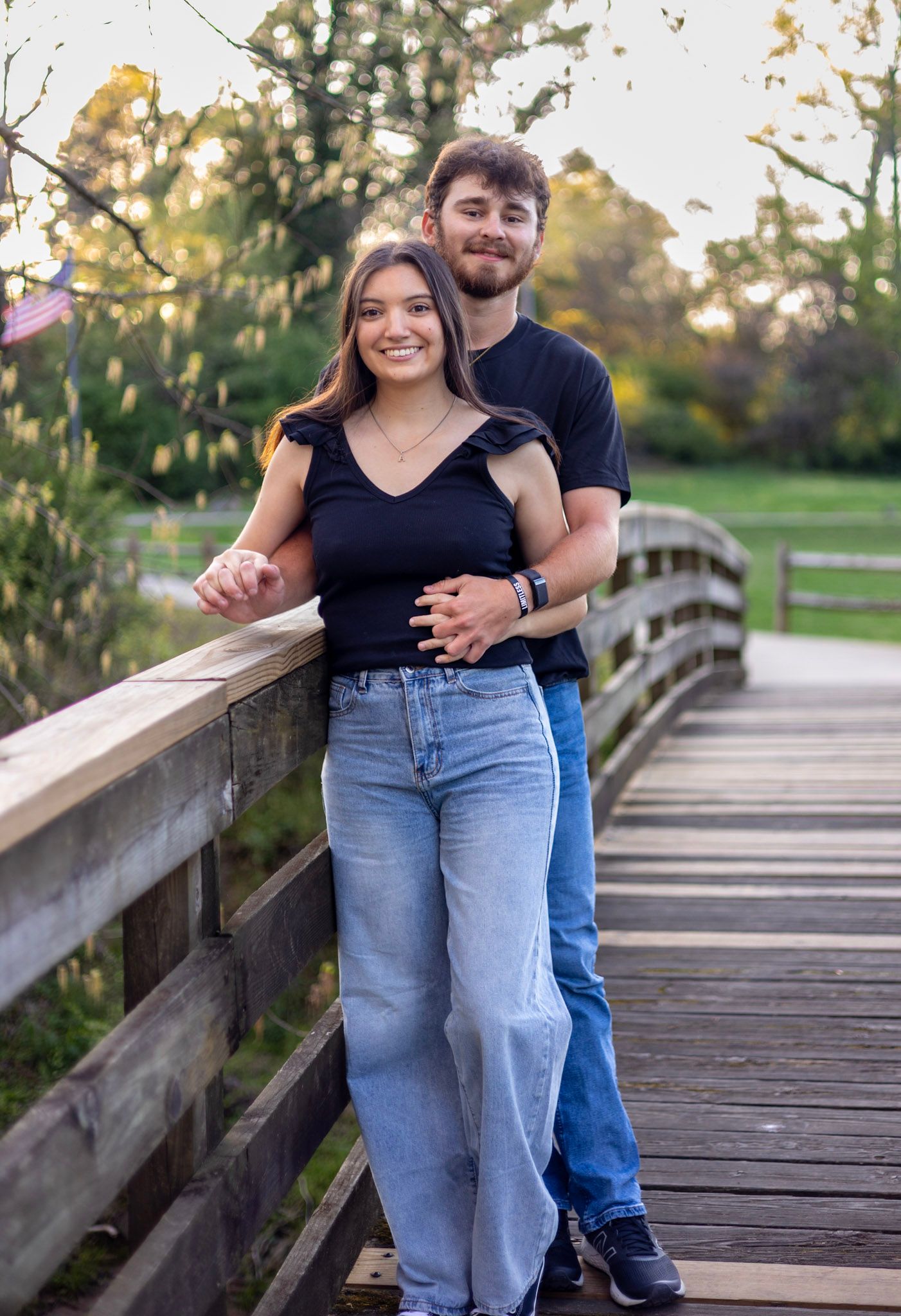 A couple shares a tender moment together while standing on a wooden bridge walkway at sunset.