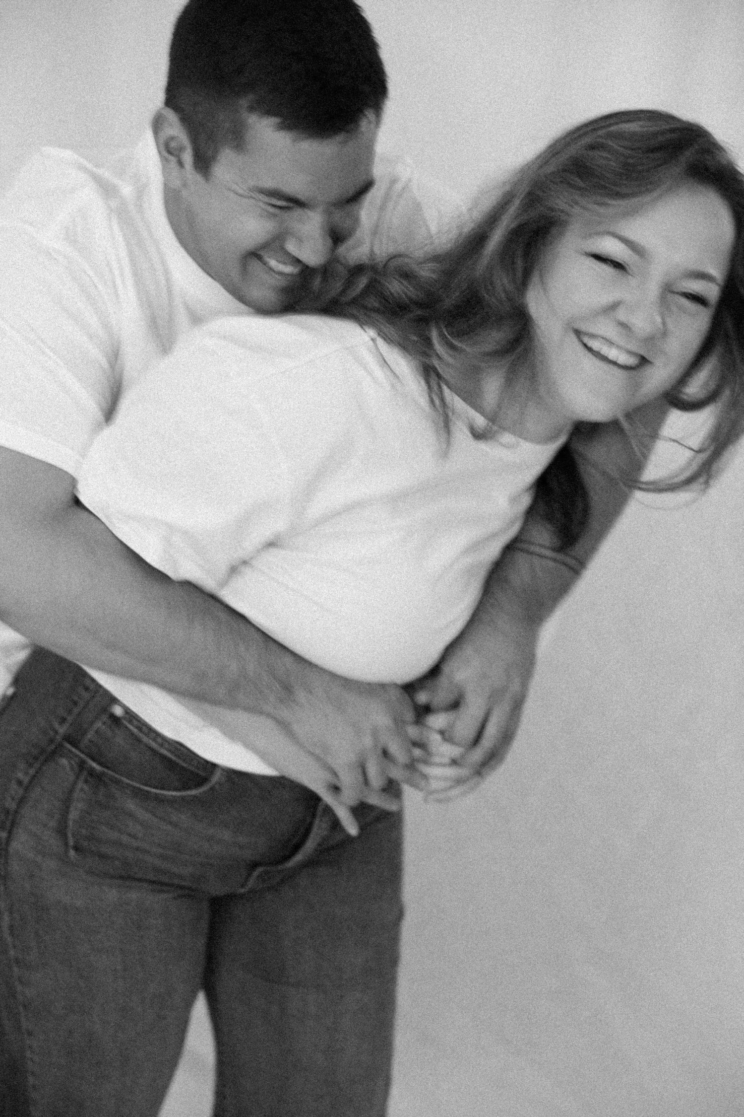 A series of black and white photos showing a close embrace between two people in casual attire against a plain background.