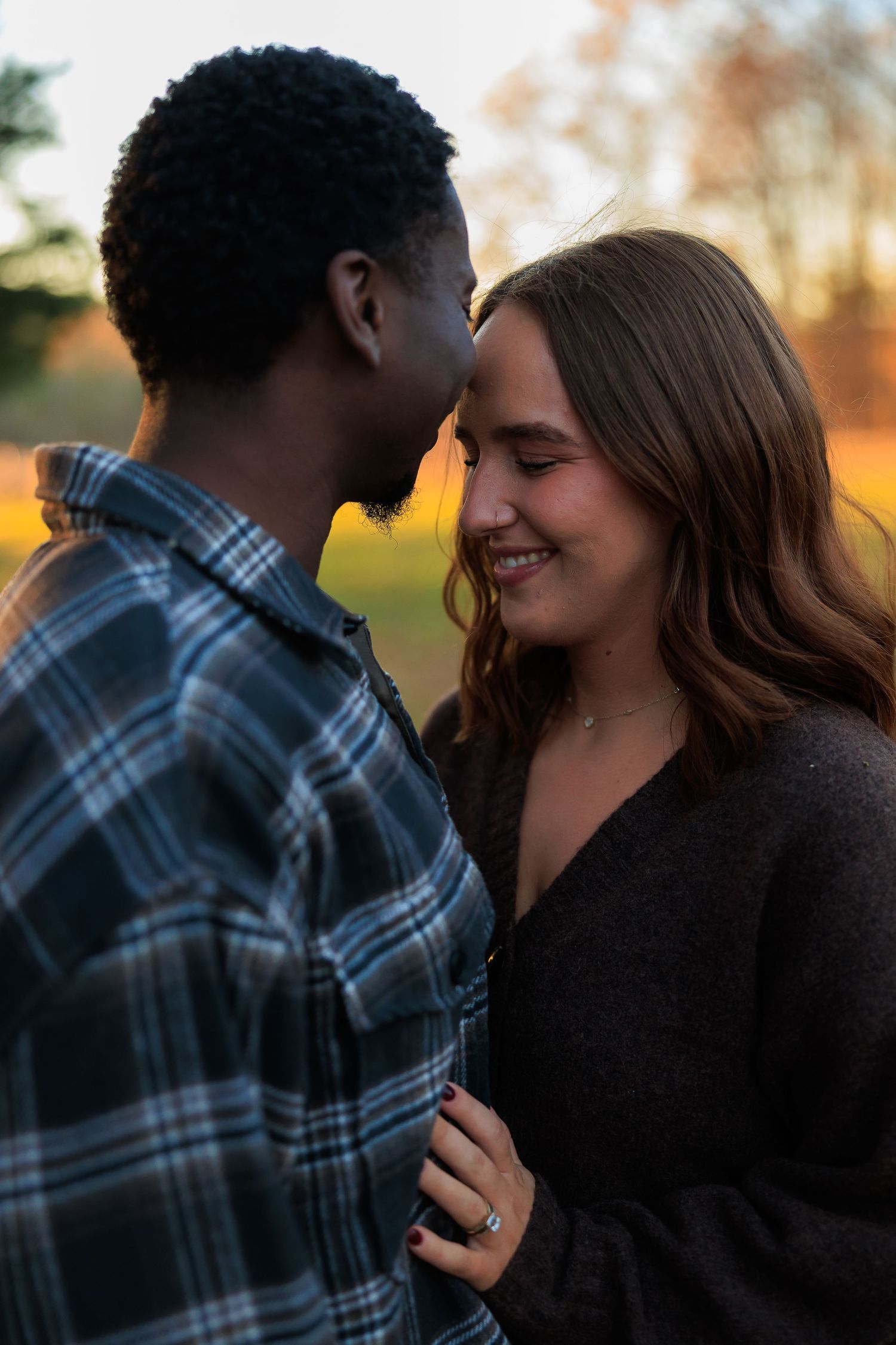 A romantic couple shares tender moments at sunset in a series of intimate poses against a warm autumn background.