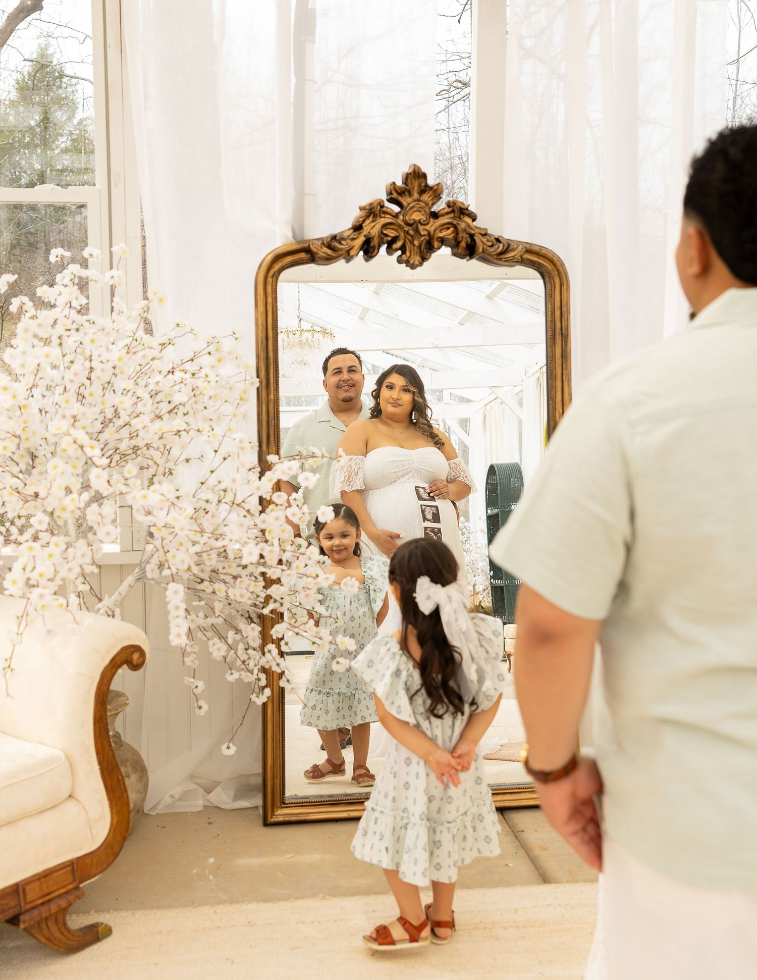 A playful photoshoot moment in a bright studio with white floral decor and a vintage mirror.