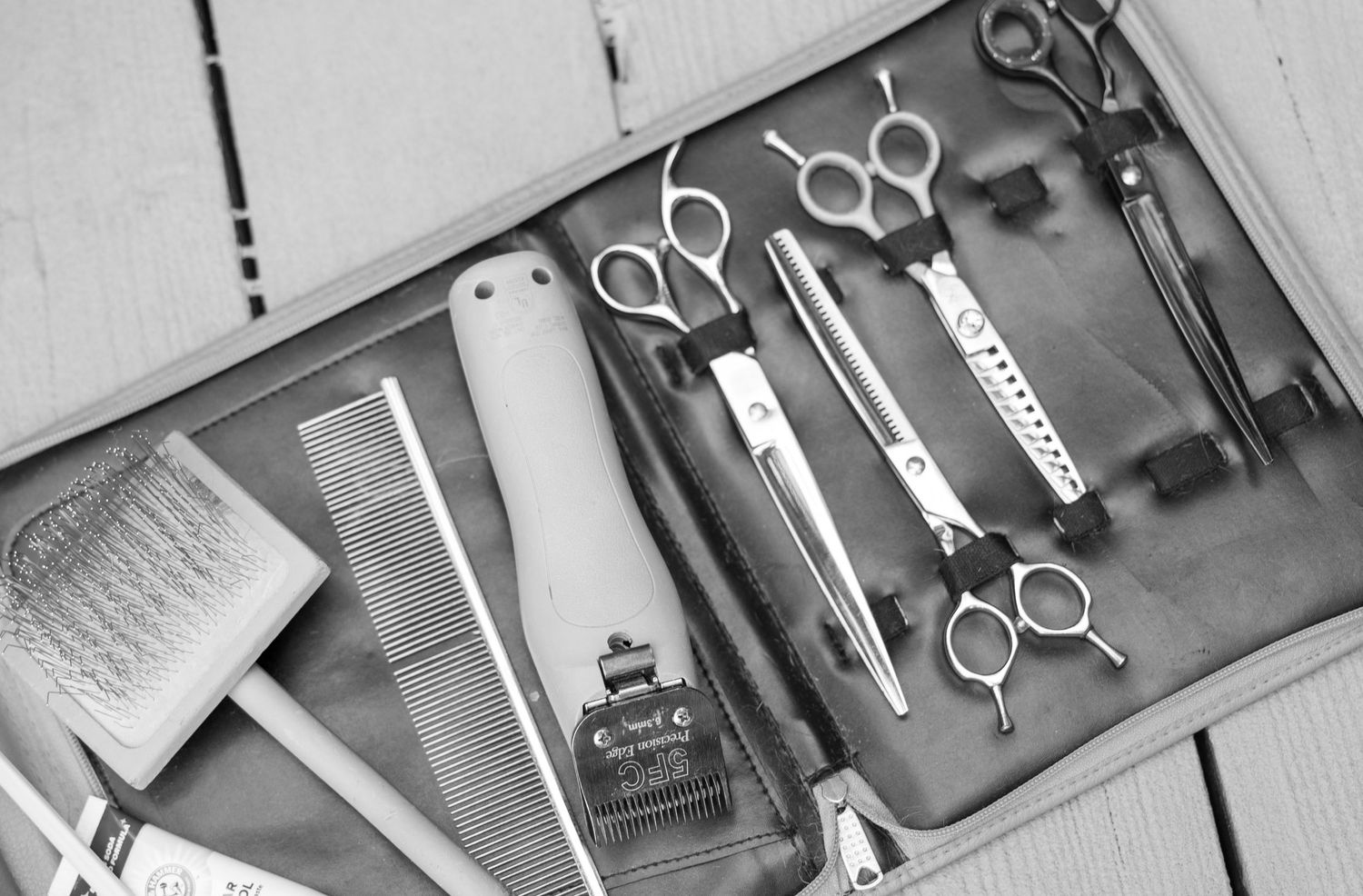 A black and white top-down view of vintage barber tools including scissors, combs, and trimming equipment laid out neatly.