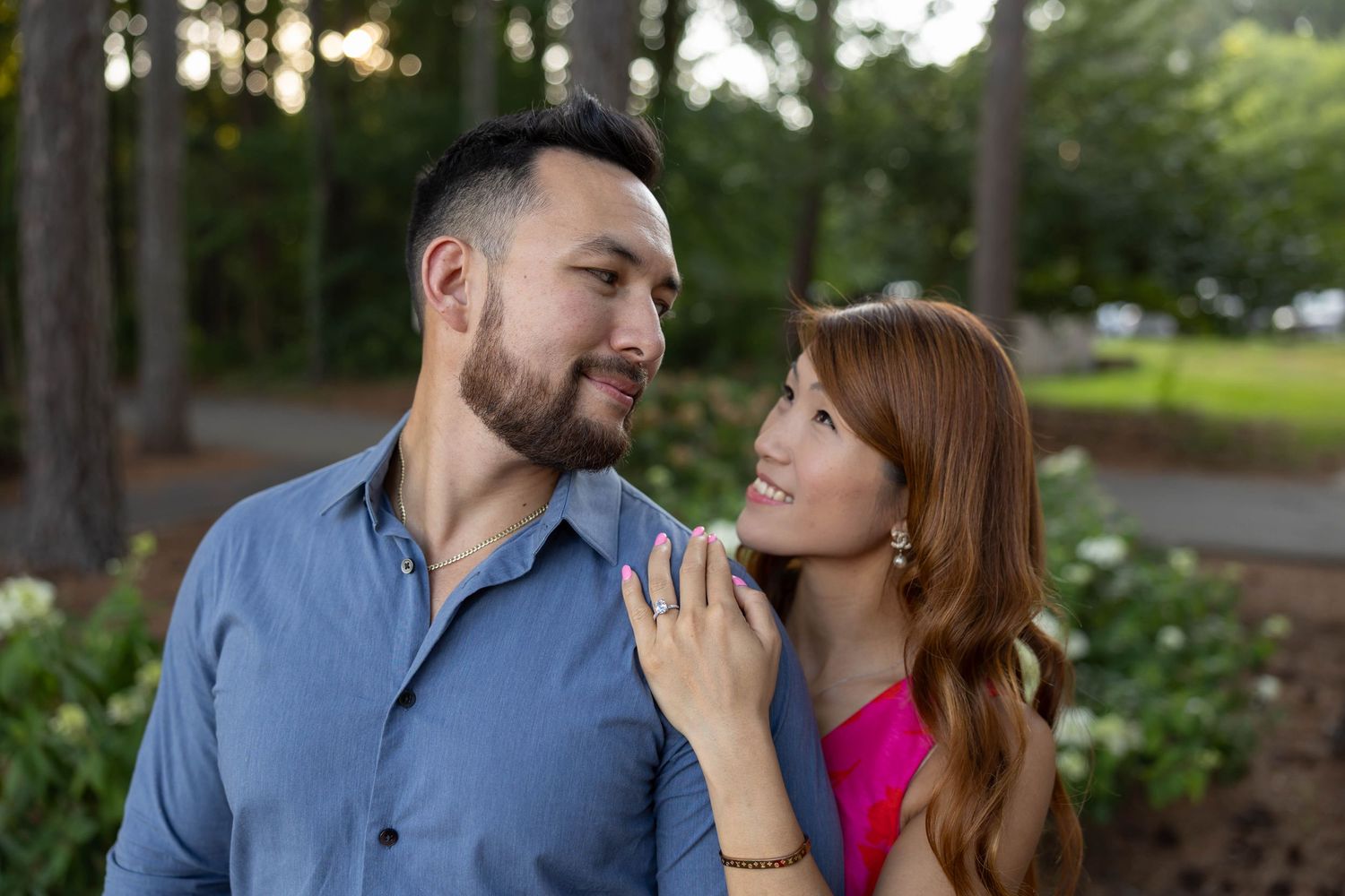 A romantic couple shares tender moments during an outdoor photoshoot in a garden setting.