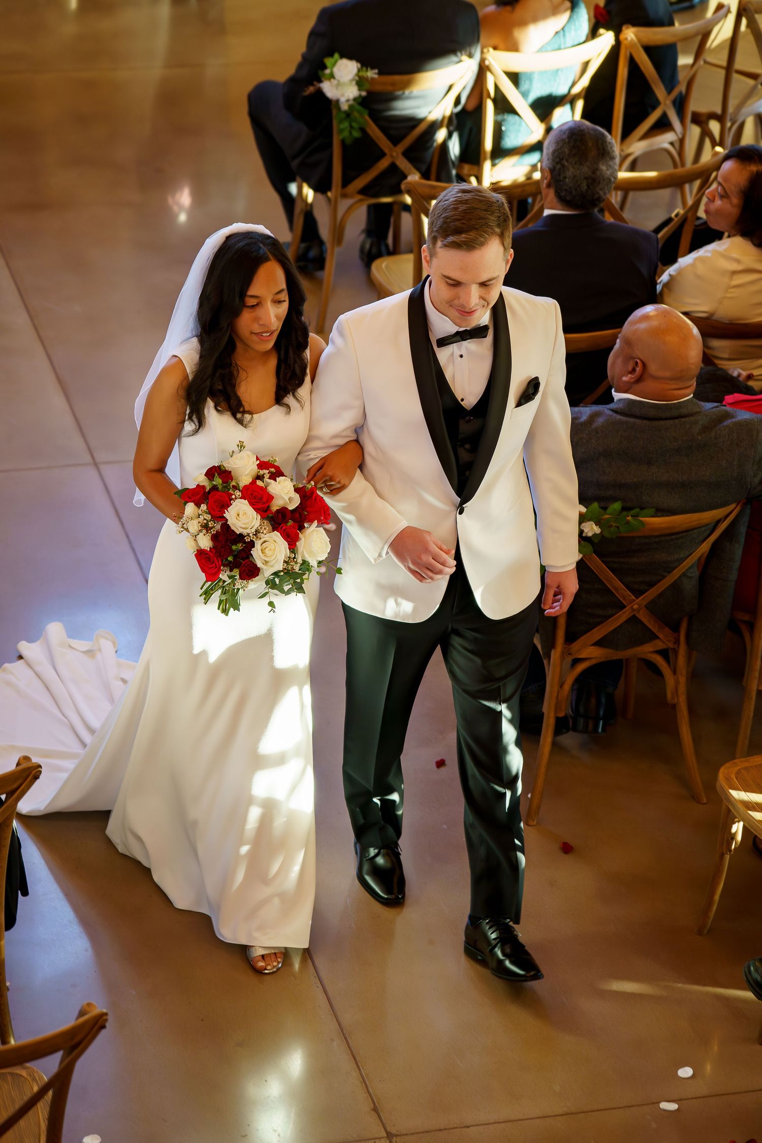 A bride and groom walk down the aisle together during their wedding ceremony in an elegant venue.