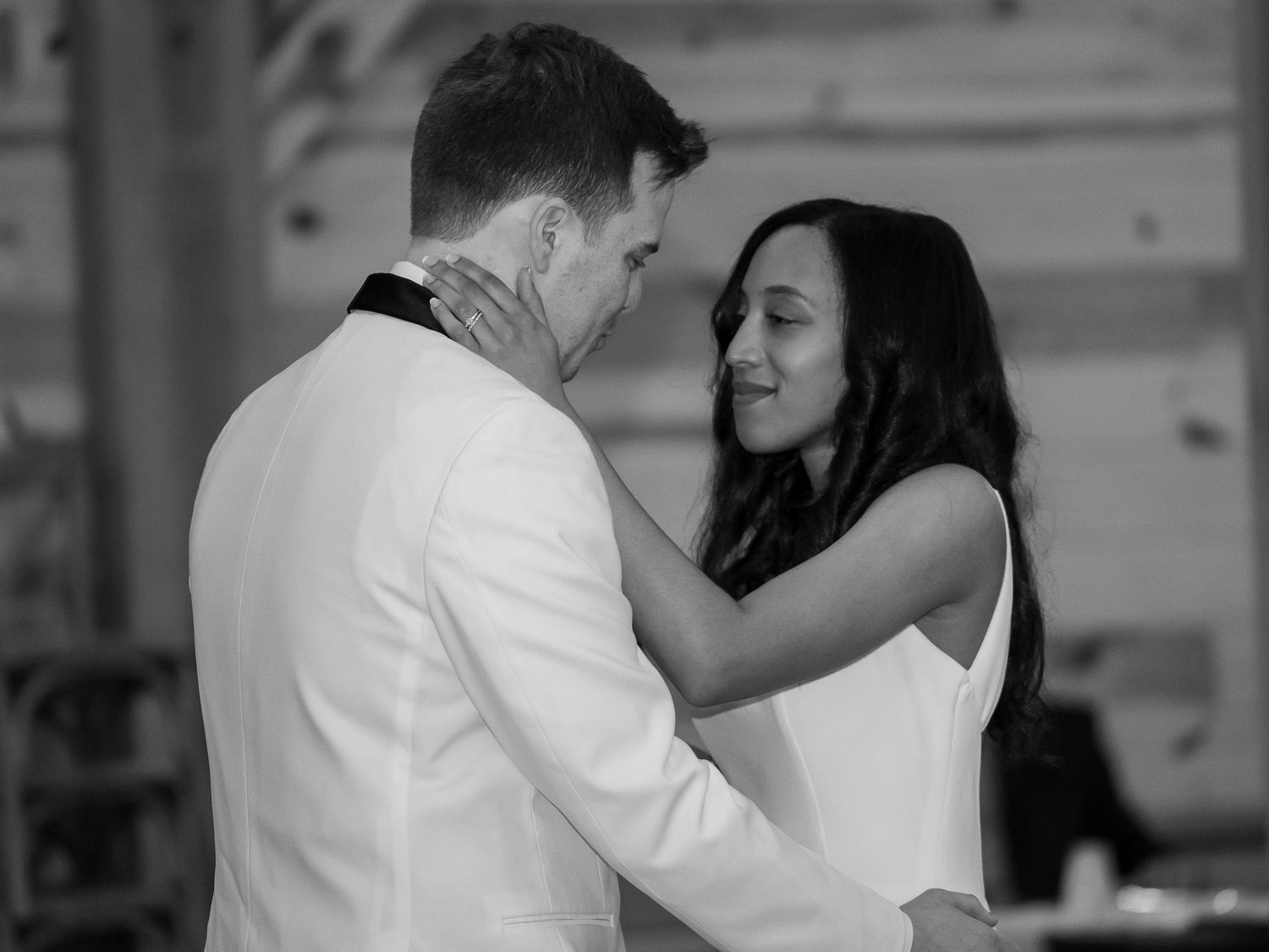 Bride and groom share intimate first dance in black and white wedding reception photo.