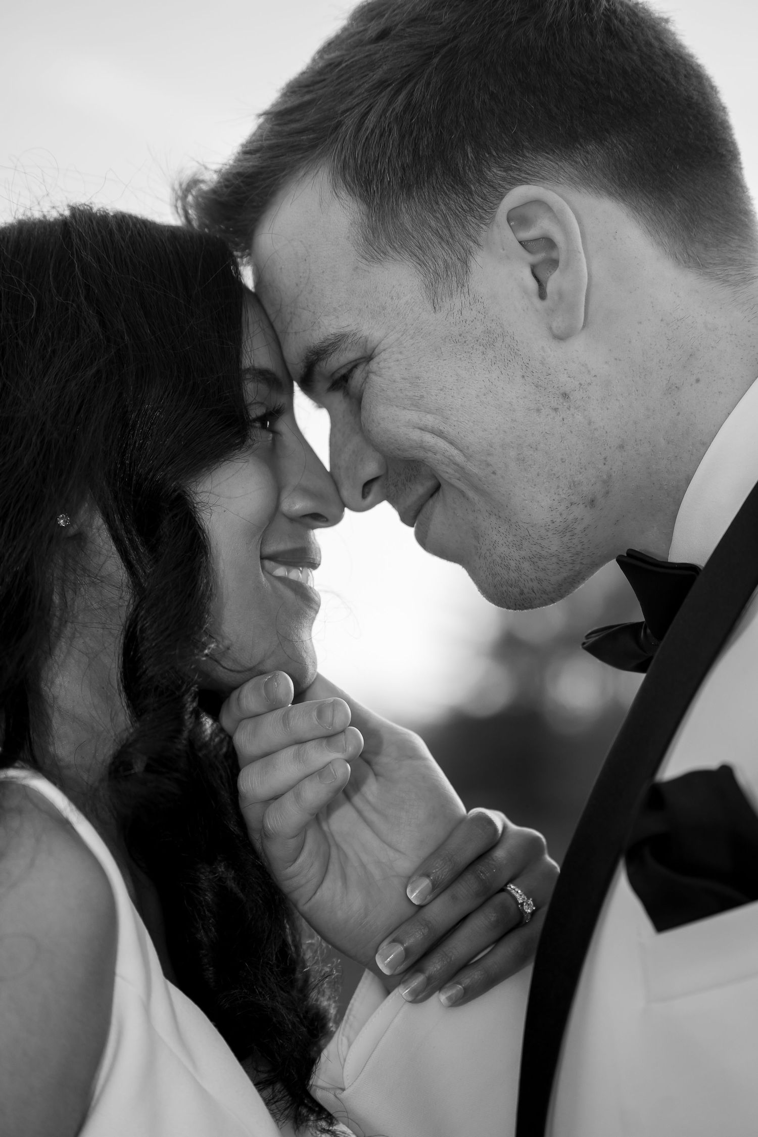 A tender black and white portrait of a couple in wedding attire sharing an intimate moment together.