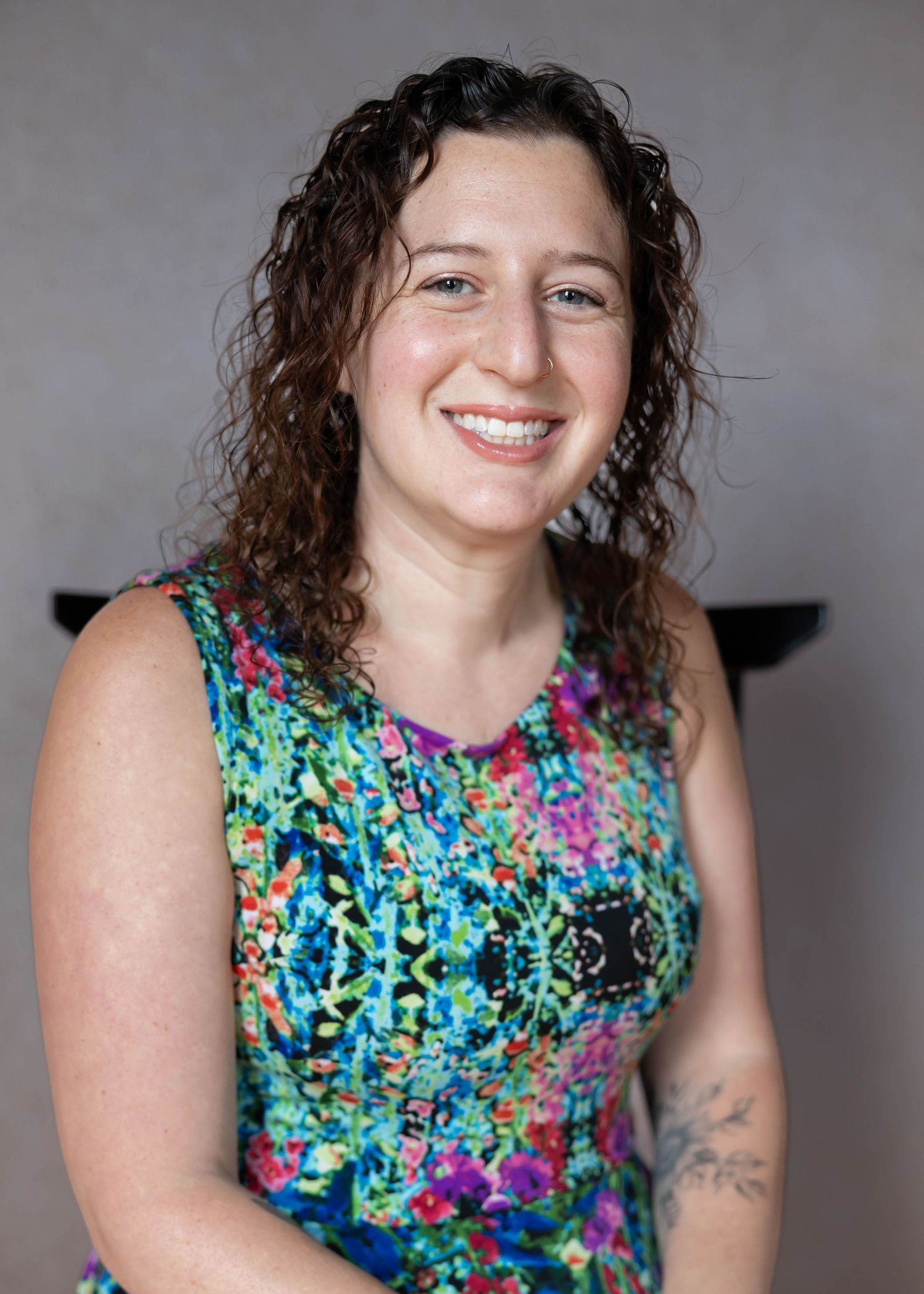 A series of portraits showing someone wearing a vibrant floral sleeveless dress against a gray background.