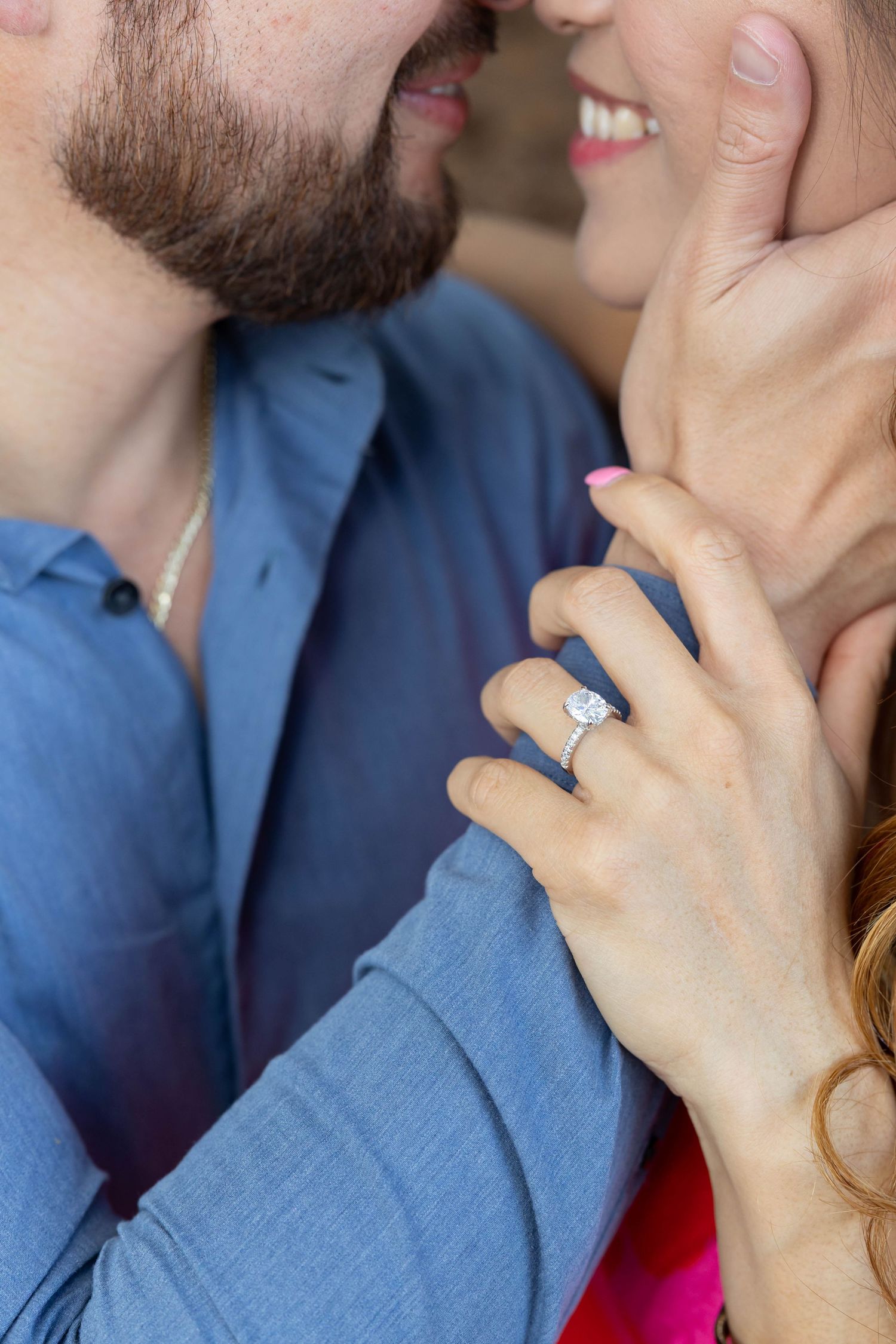 Close-up photo showing a couple embracing with the woman wearing an elegant diamond engagement ring.