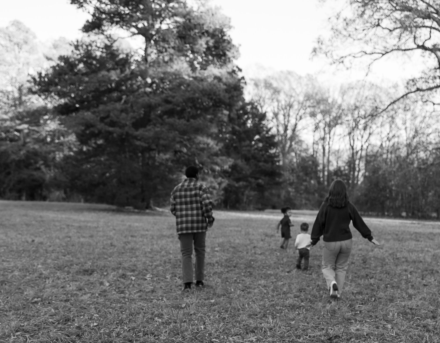 A series of black and white photographs showing people walking and playing in a grassy field with trees in the background.