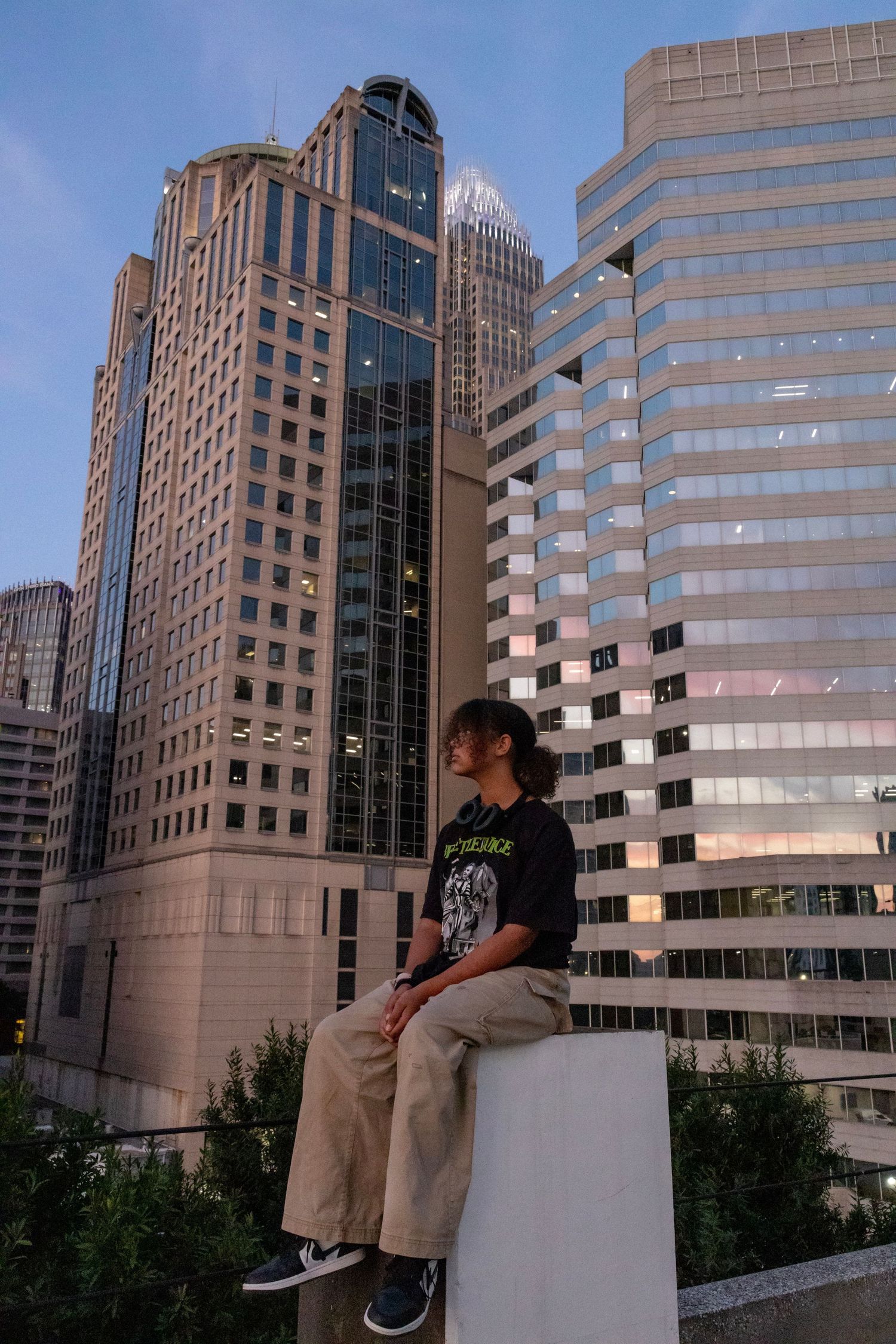 Urban cityscape with tall modern office buildings and skyscrapers in downtown area at dusk.