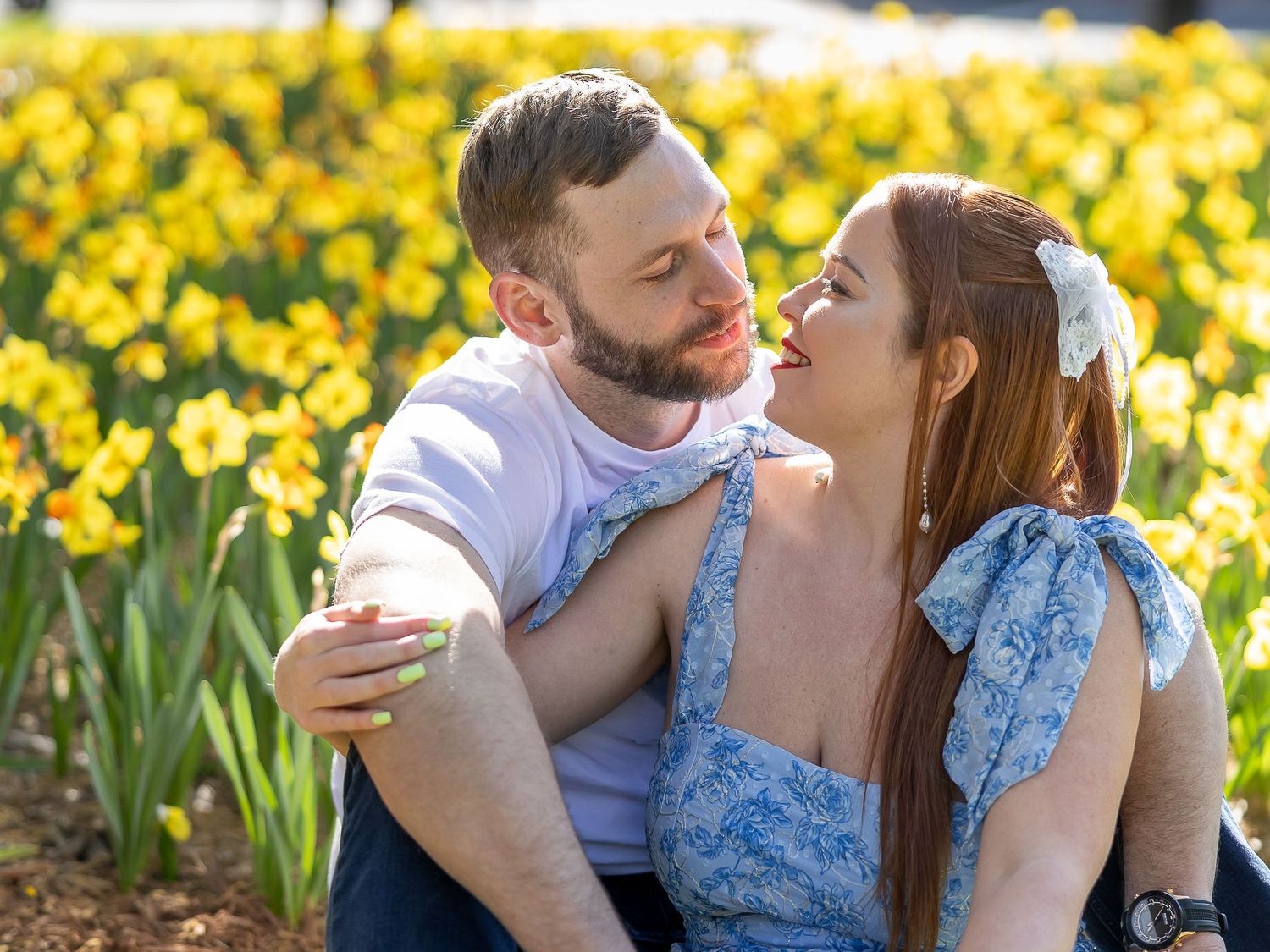 A young couple embracing affectionately in a field of yellow daffodils.