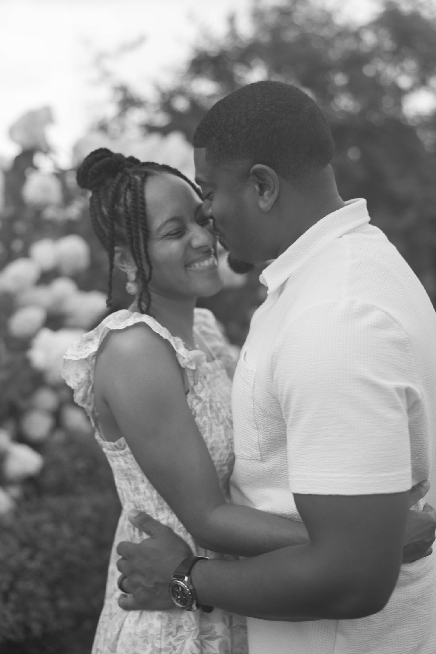 A series of romantic black and white photos showing a couple embracing tenderly in an outdoor garden setting.