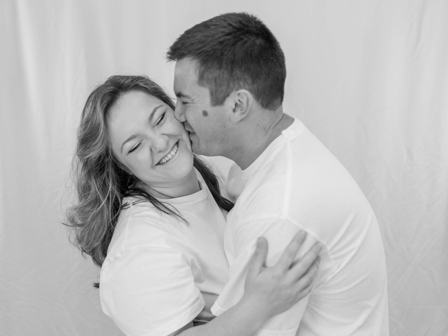 A series of romantic black and white photos showing an intimate couple embracing and kissing in white clothing.