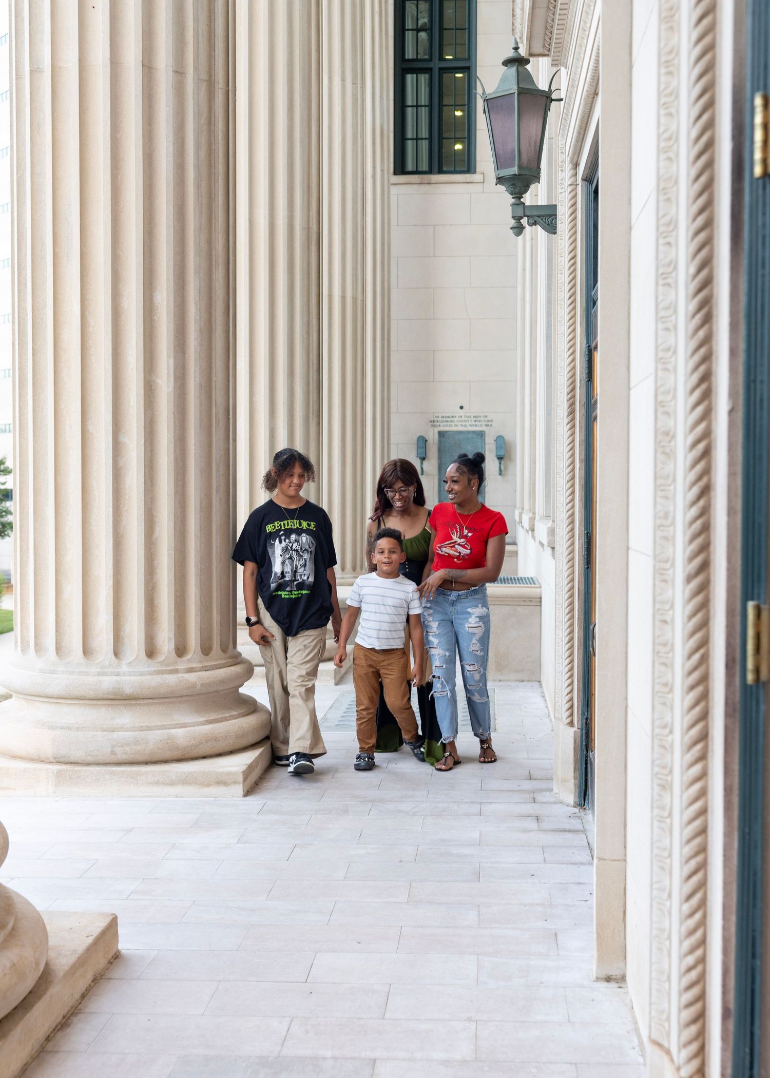 A group stands together in a breezeway between classical stone columns at a stately building entrance.