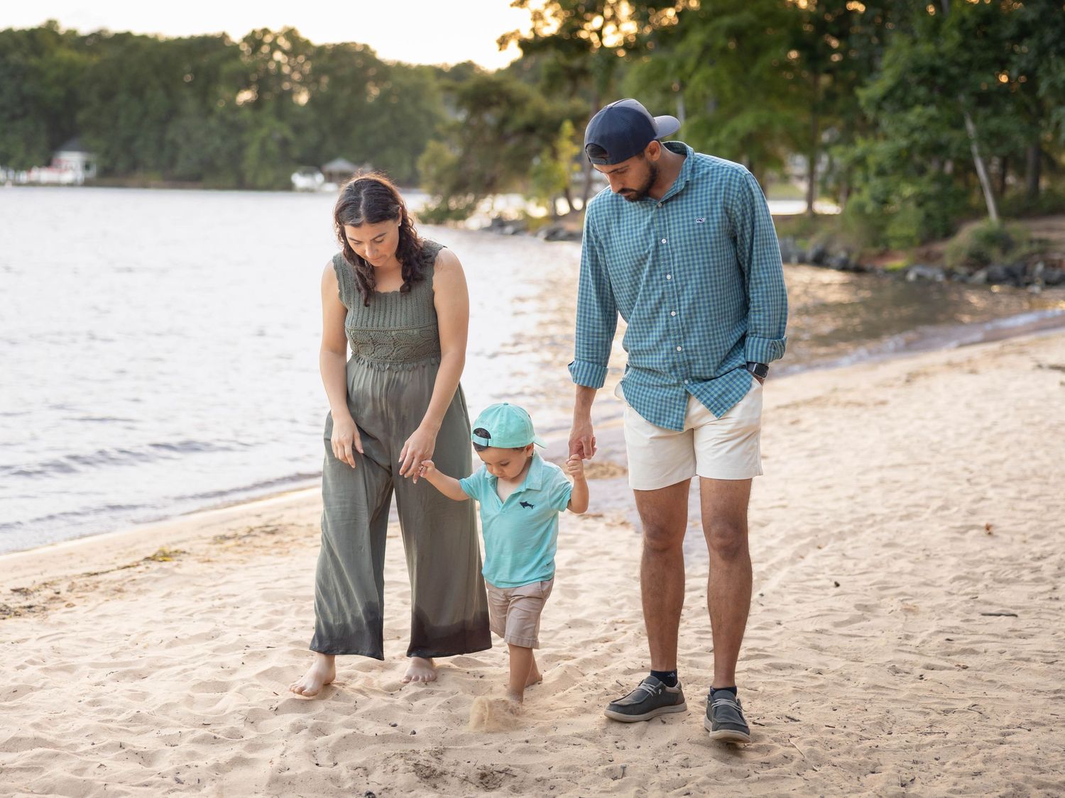 Family spending quality time together walking barefoot on a sandy beach at sunset as waves roll in.
