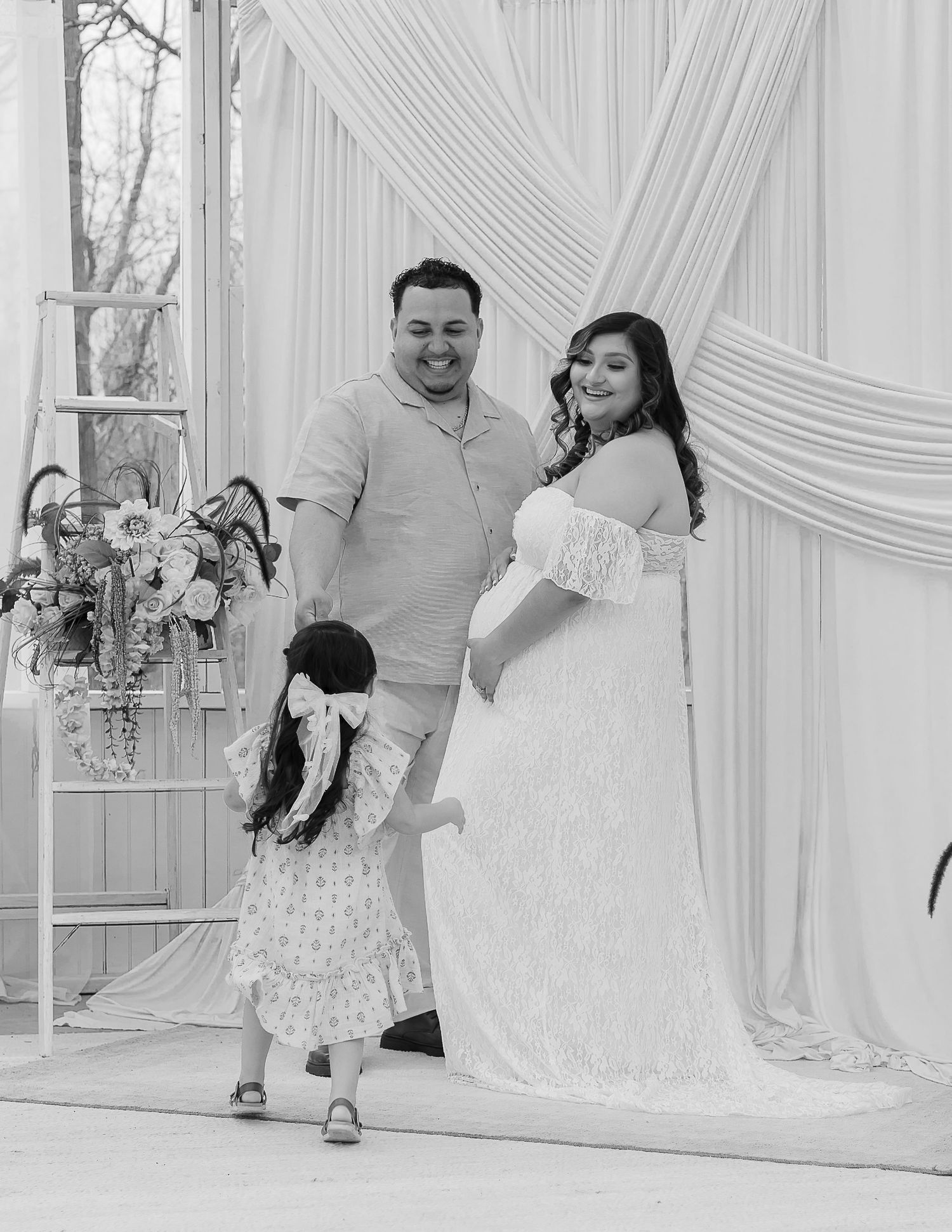 A series of black and white wedding photos showing tender moments between a couple in a white draped setting.
