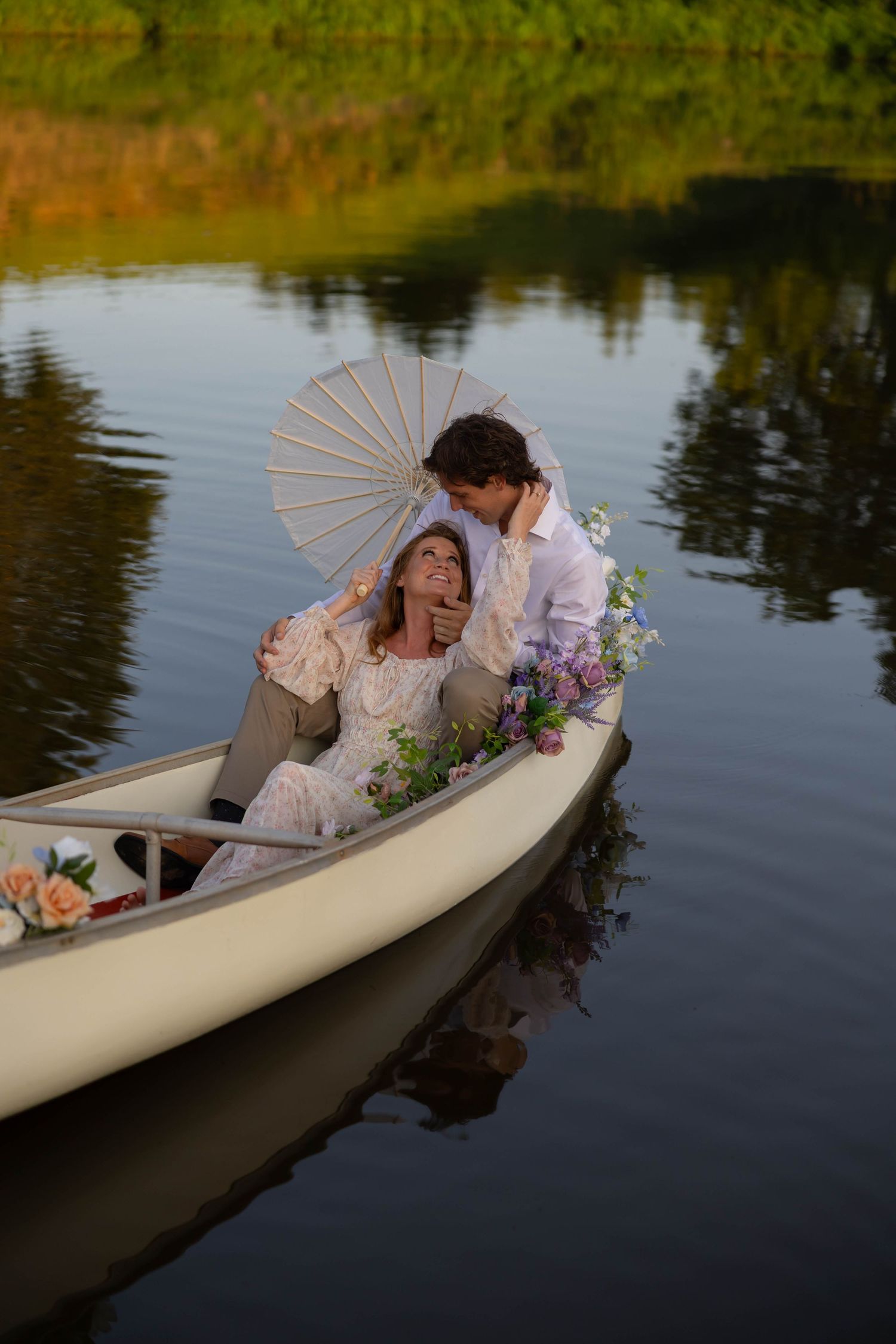 A vintage-styled scene with a white canoe on calm waters featuring decorative parasols and floral arrangements.