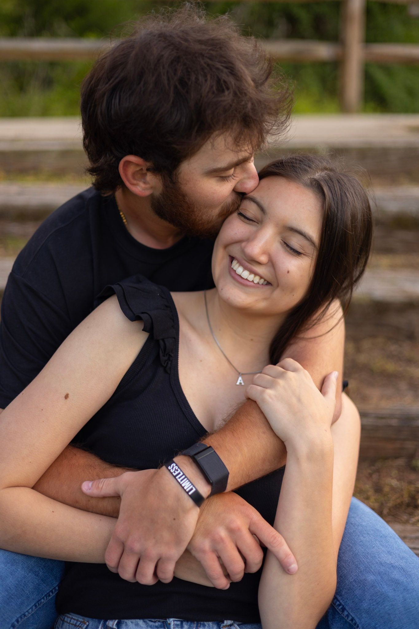 A couple shares a tender embrace while sitting on wooden benches outdoors.