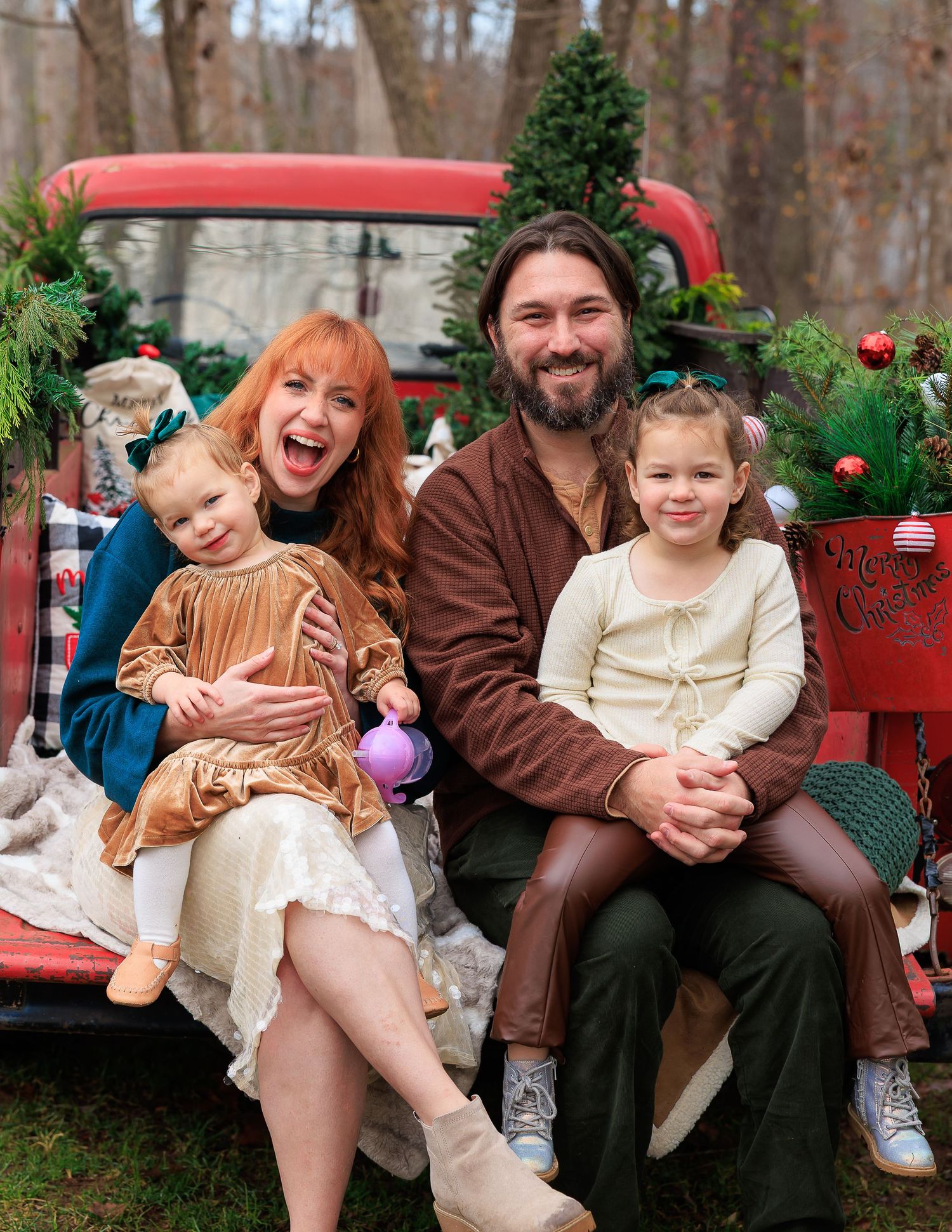 A collection of festive family portraits on a red bench surrounded by Christmas trees and holiday decor.