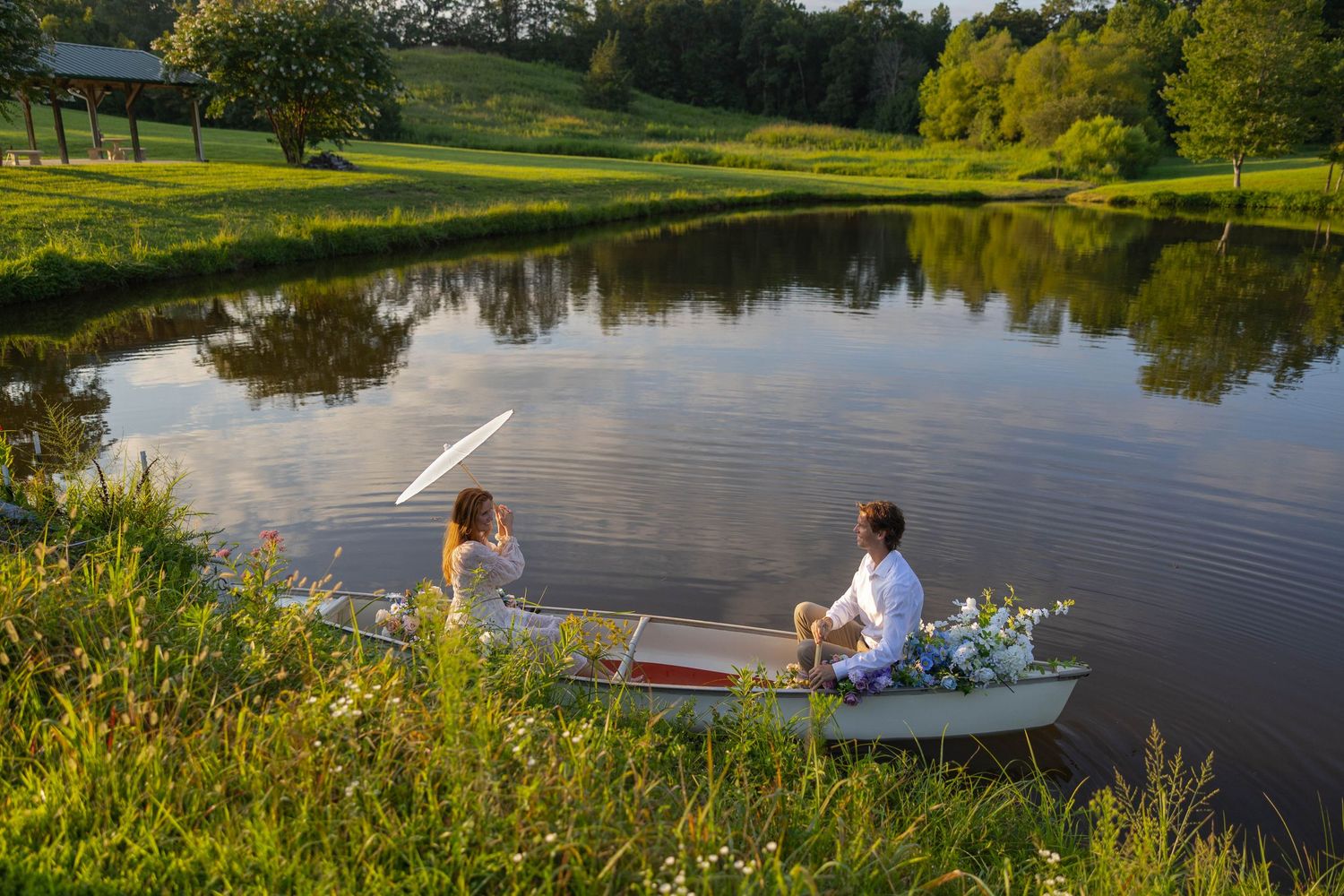 A serene lake surrounded by lush greenery with people enjoying leisure activities along the shoreline.