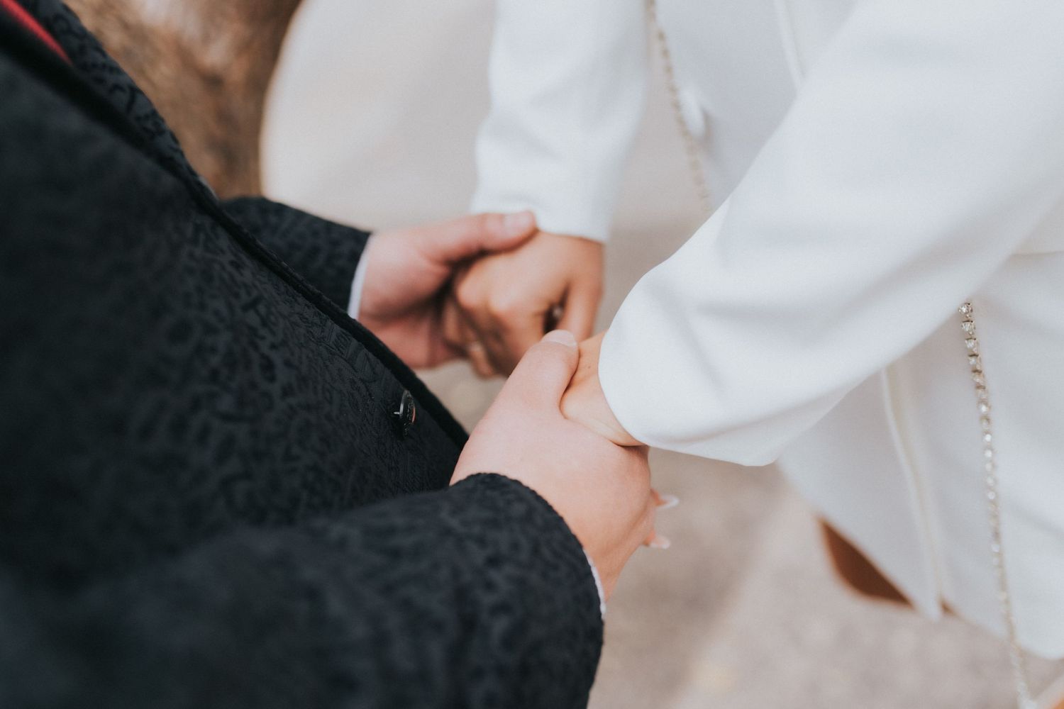 Close up of two people holding hands together, wearing black and white clothing.