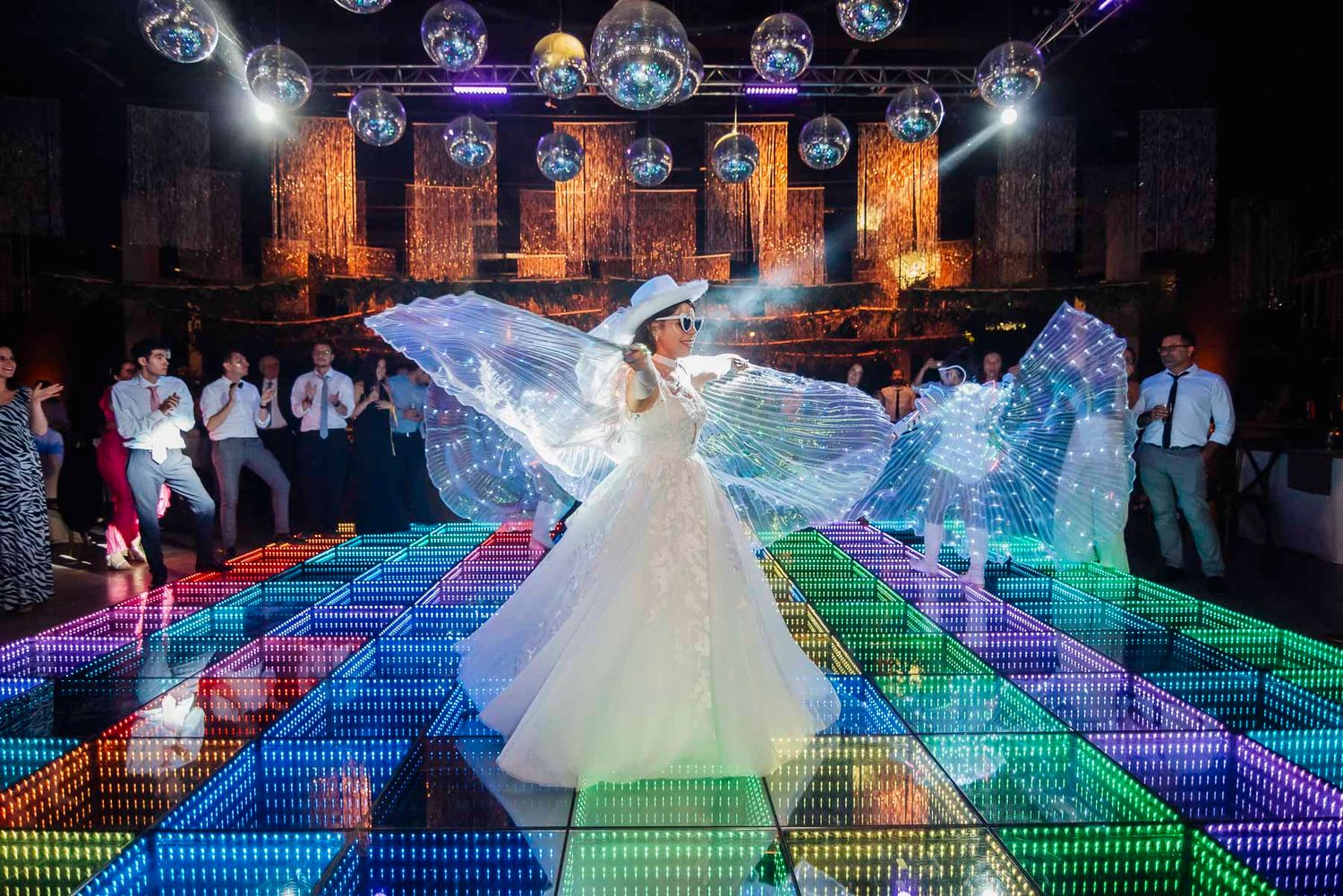 Colorful LED dance floor illuminates a grand ballroom setting with dramatic lighting effects for a wedding celebration.