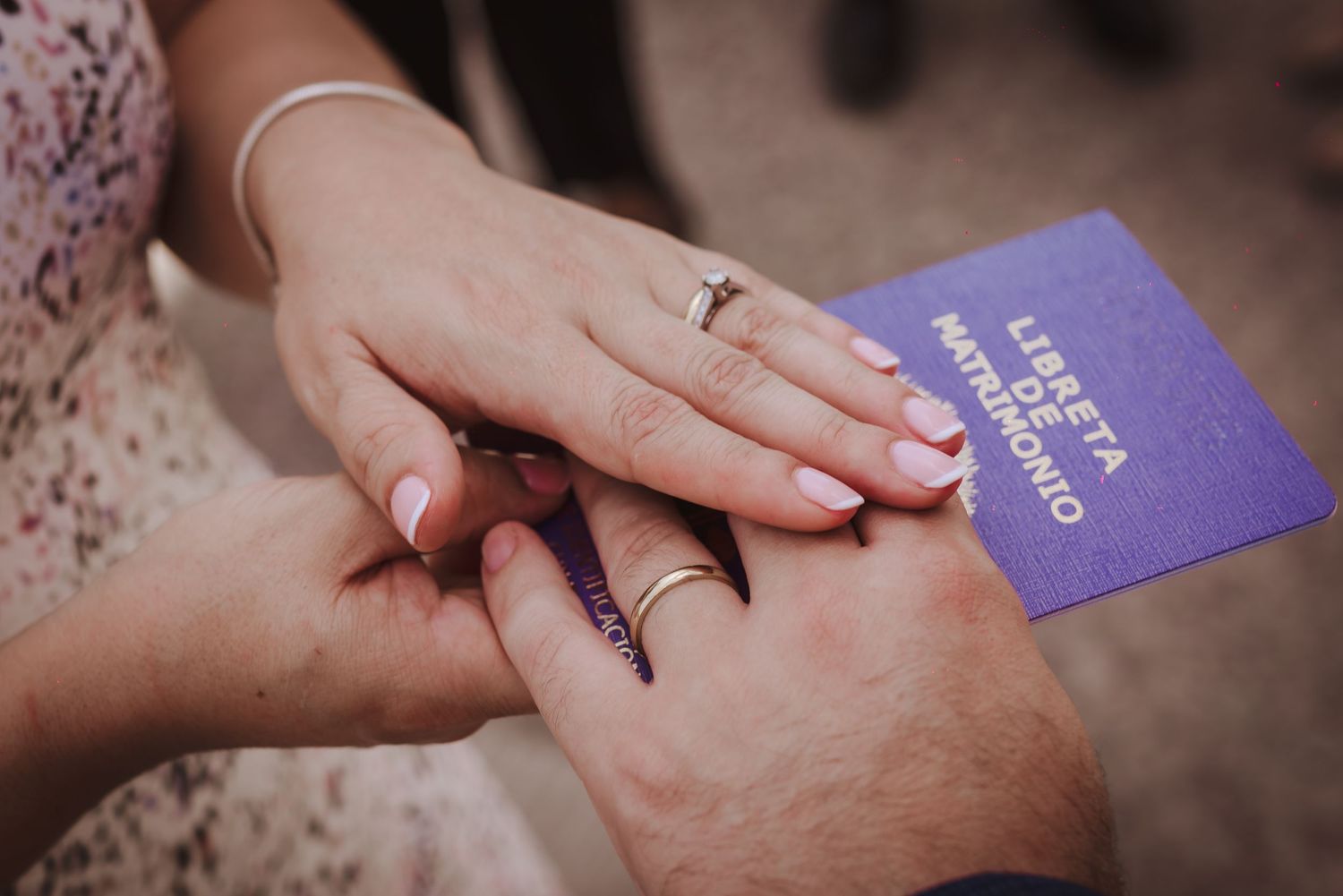 Two hands exchanging a purple marriage license while showcasing beautiful wedding rings and nail polish.