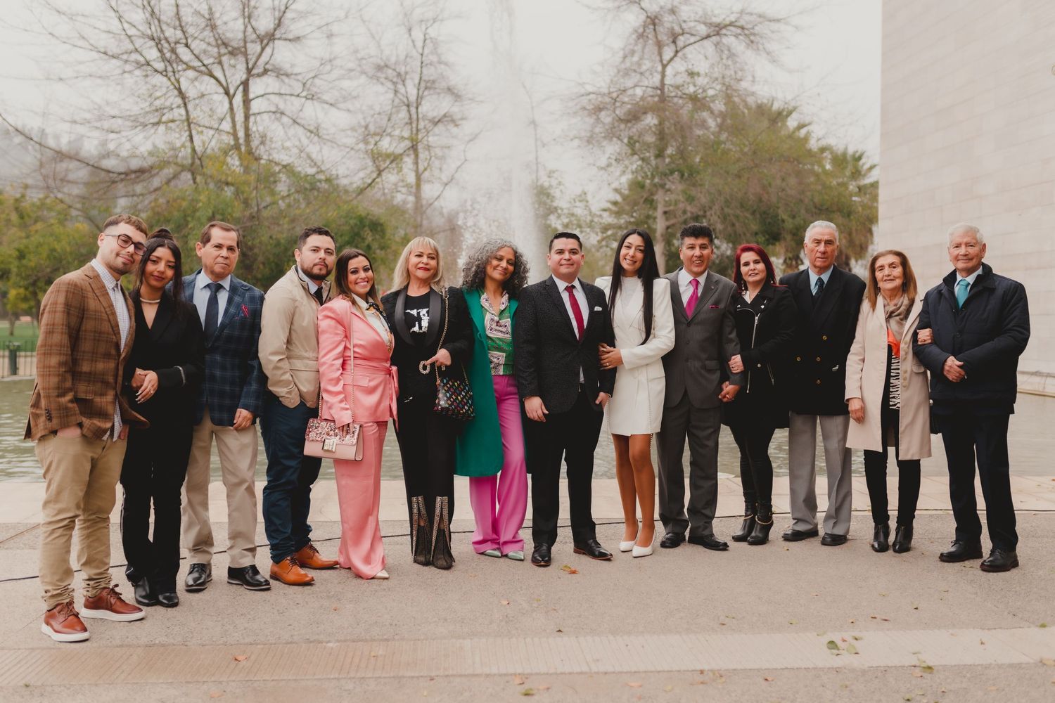 A group of people standing together outdoors in formal attire for a special occasion during autumn.